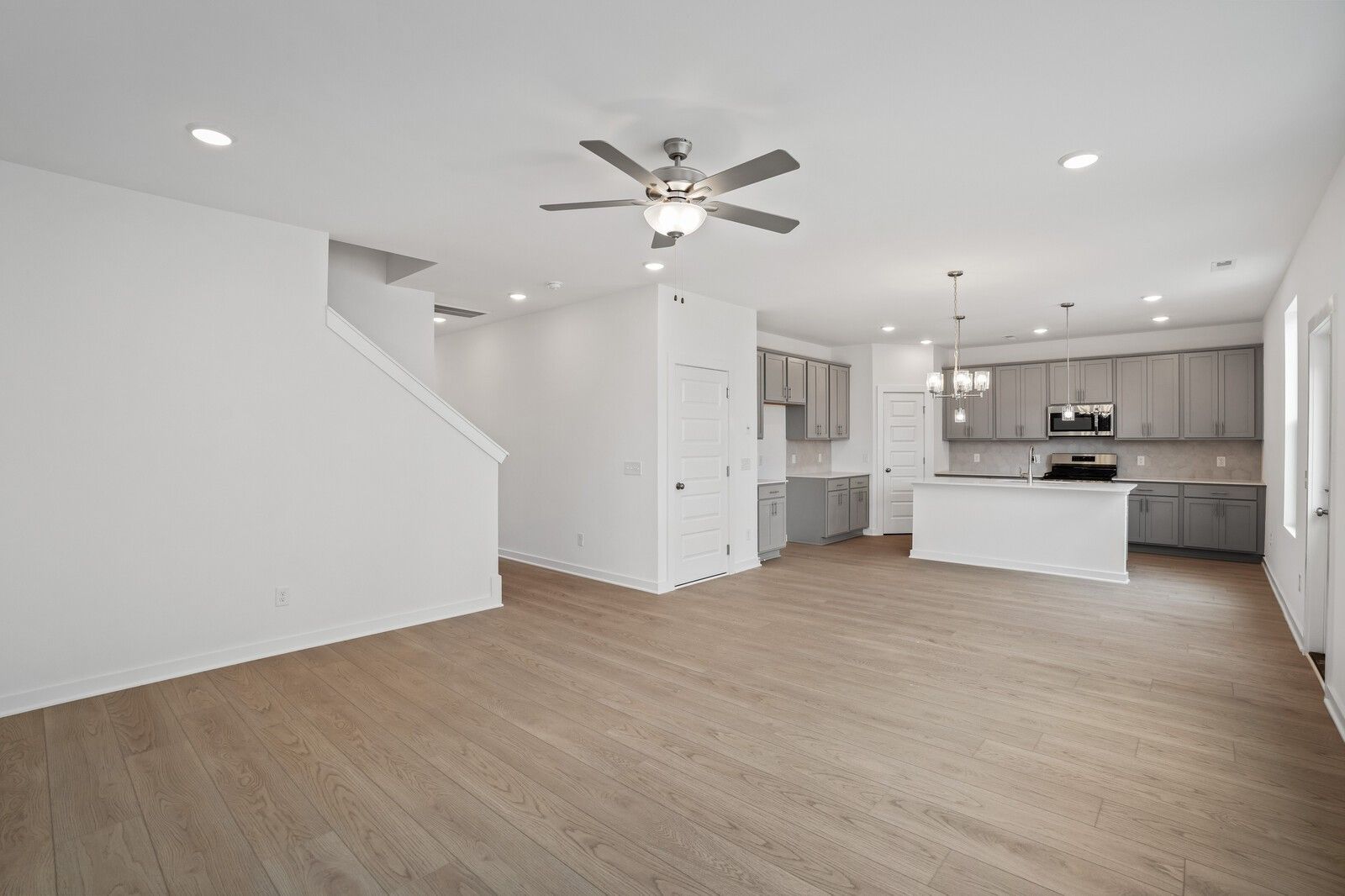 Open-concept living area and kitchen with grey cabinets in The Logan C floor plan at Calista Farms, White House, Tennessee.