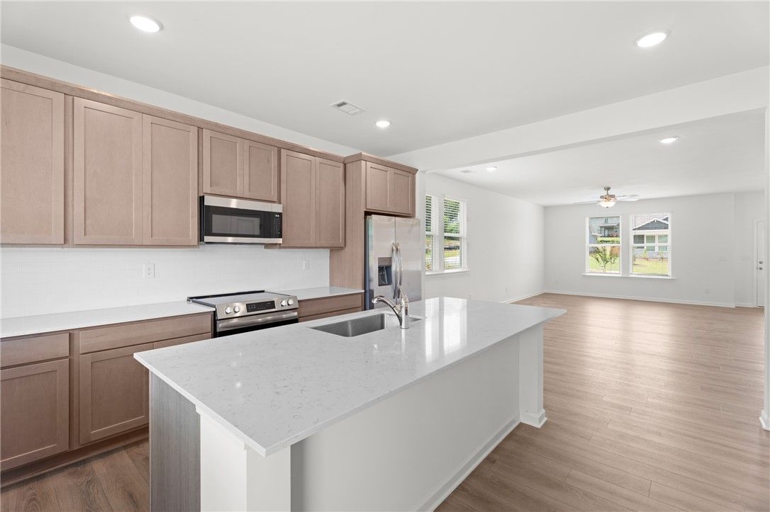 Open-concept kitchen with quartz island and stainless appliances in The Stella D floor plan at Silver Oak, Cusseta, Alabama.