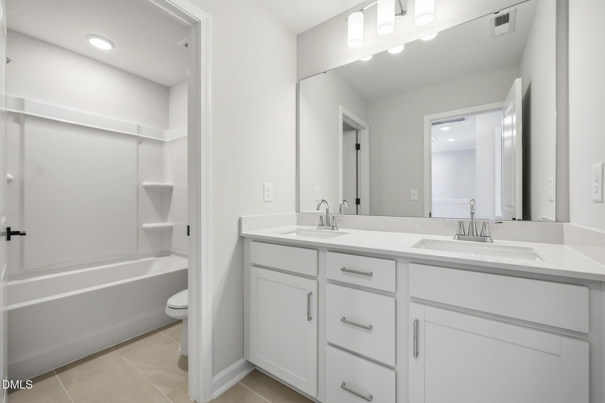 Modern bathroom with double vanity and tub-shower combo in The Avery floor plan at Forestville Yard Townhomes, Knightdale.