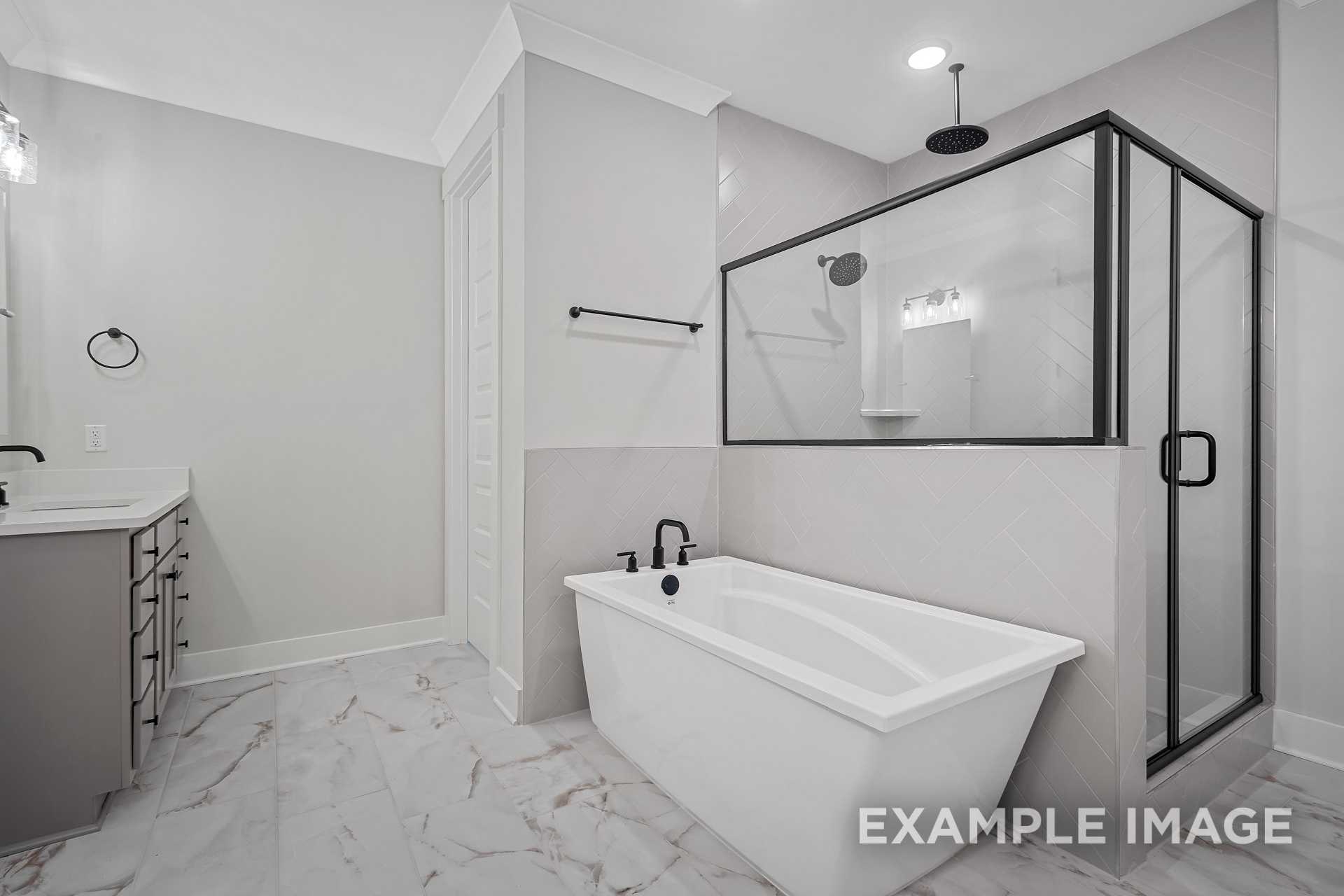 Luxurious master bathroom in The Hathaway with freestanding tub, glass walk-in shower, and marble-look flooring