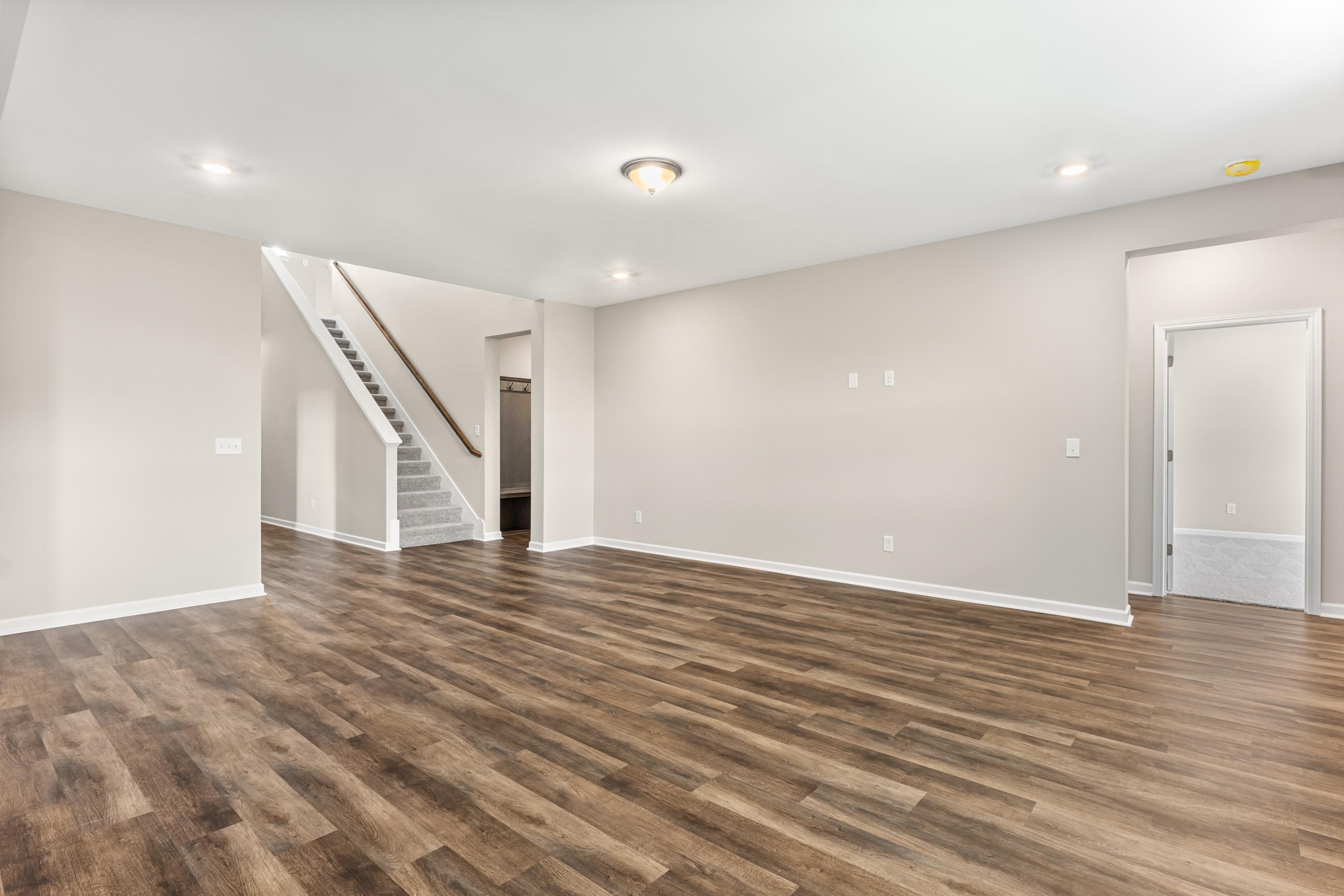 Spacious open entryway in The Haven E home with beige walls, hardwood floors, white staircase, and recessed lighting