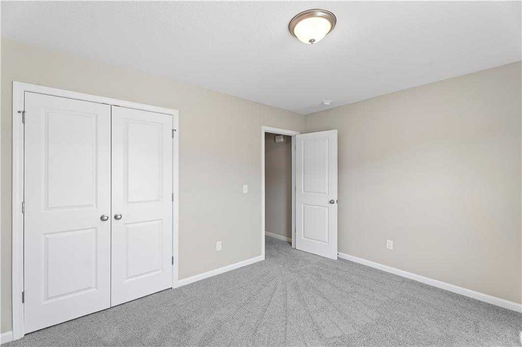 Neutral bedroom with beige walls, gray carpet, double closet doors, and bath access in Davidson Homes The Washington, Phenix City