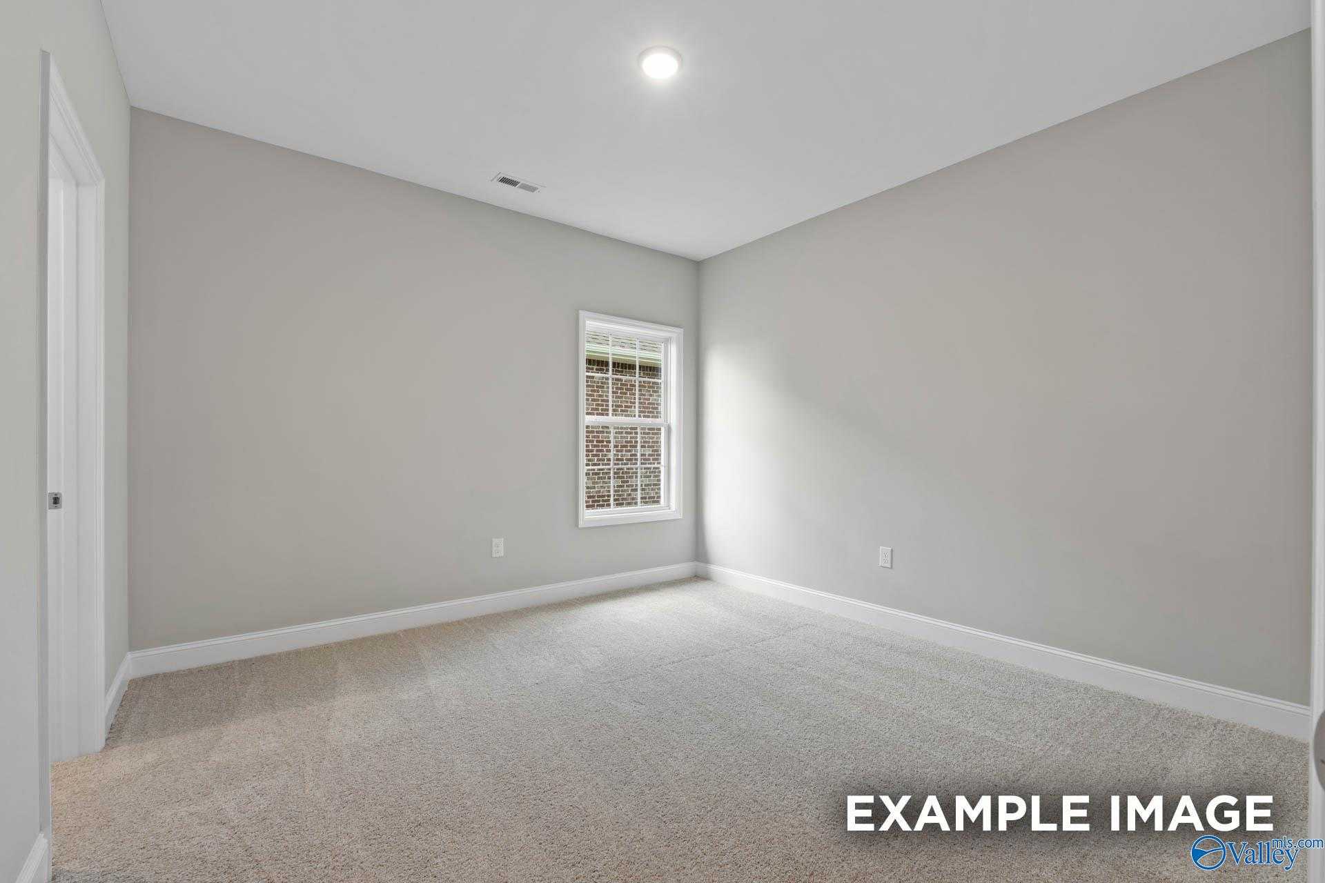 Bright secondary bedroom with light gray walls, large window, and beige carpet in The Montgomery floor plan, Meridianville, Alabama