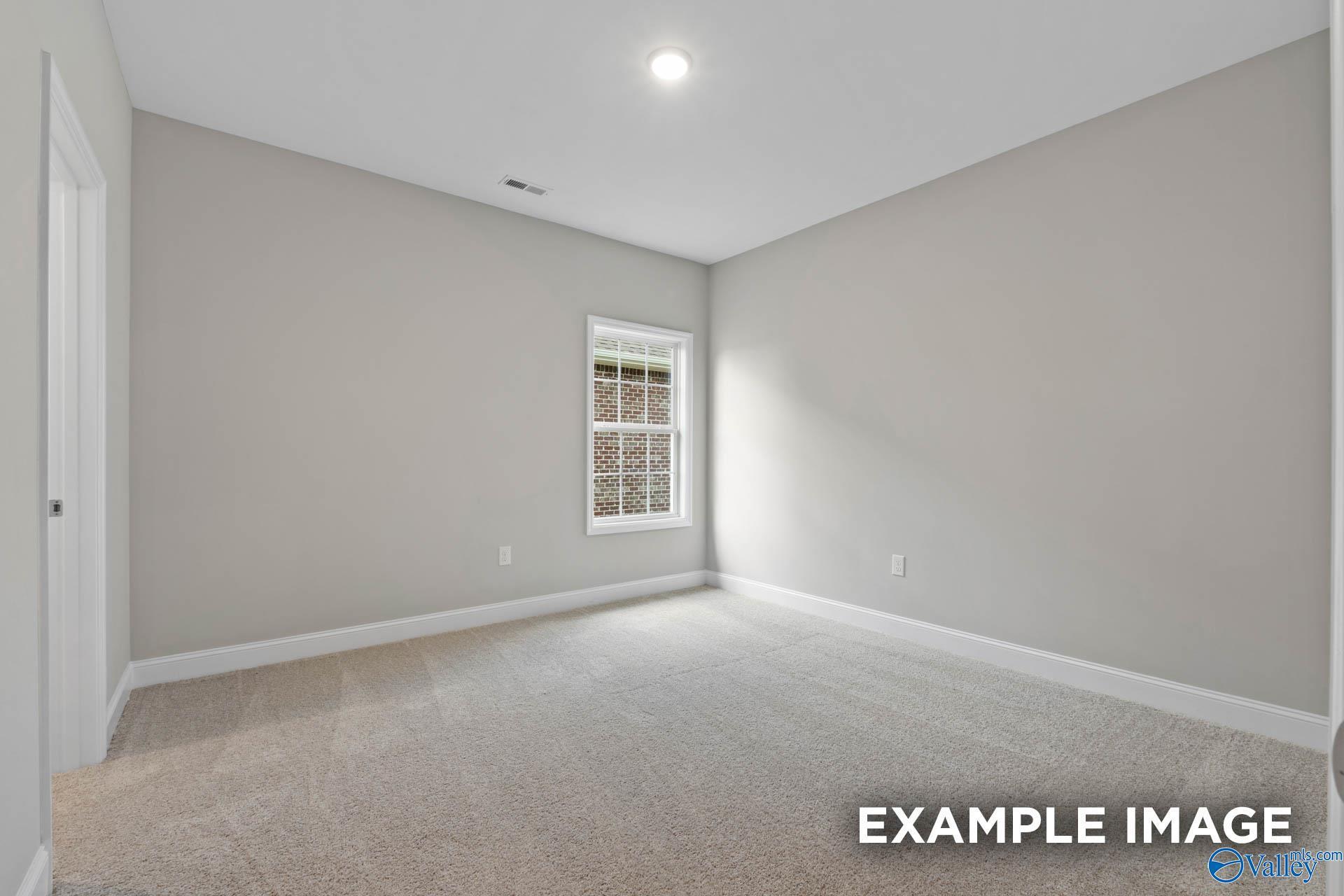 Bright secondary bedroom with light gray walls, large window, and beige carpet in The Montgomery floor plan, Meridianville, Alabama