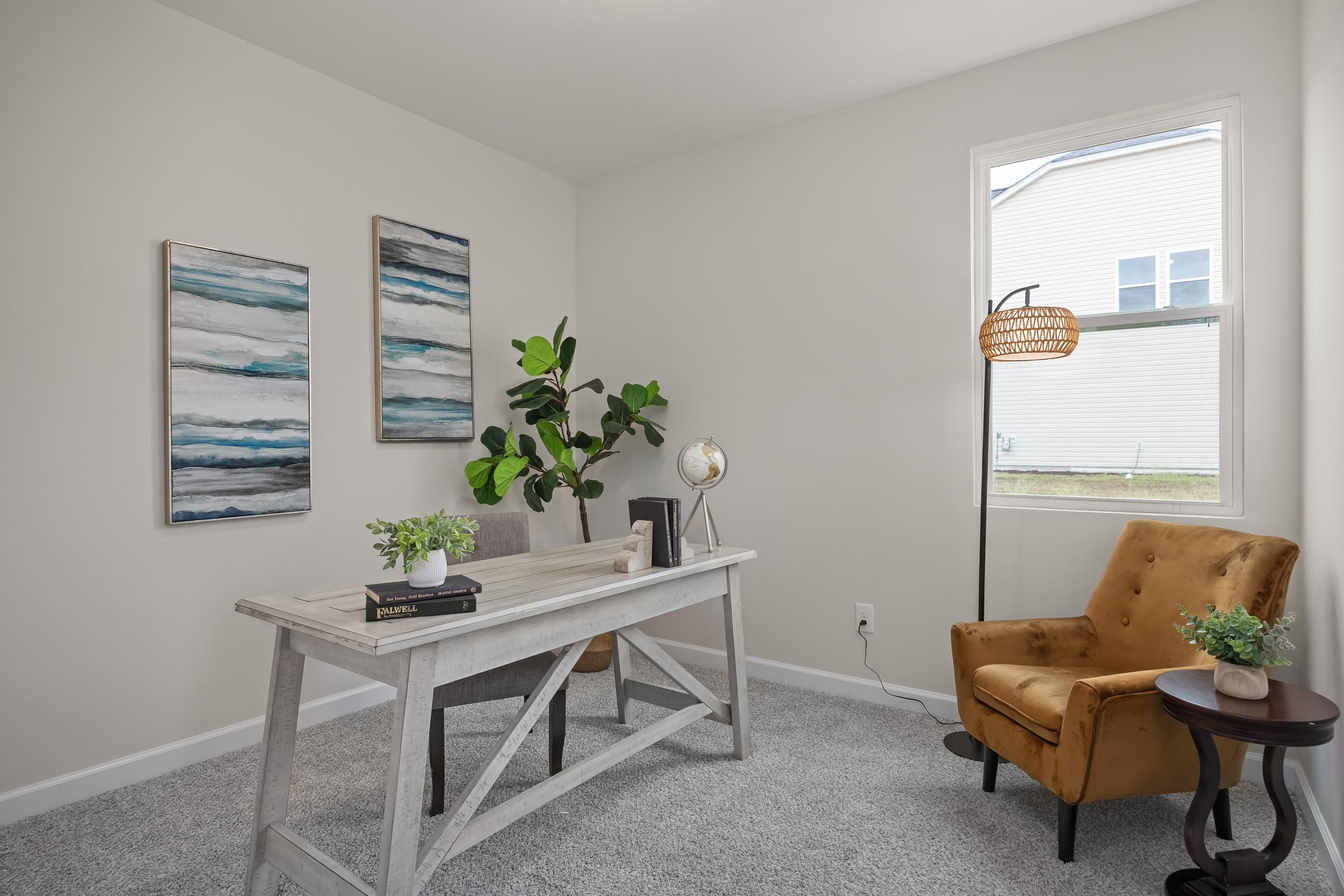 Bright home office at Gregory Village in Lillington, NC by Davidson Homes featuring a rustic desk and velvet accent chair.