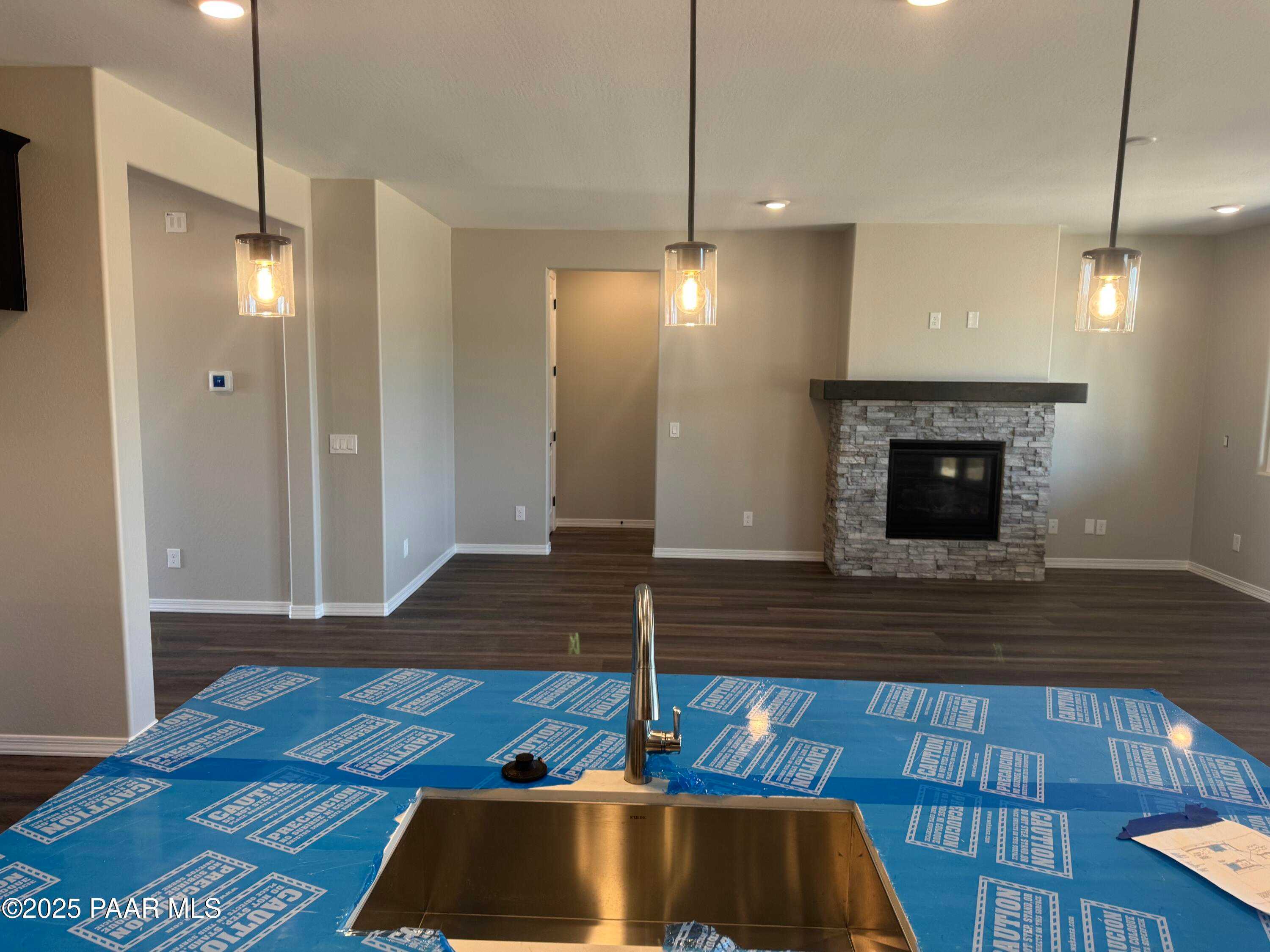 Open kitchen with stainless steel sink on blue-protected island and stone fireplace in Davidson Homes Durango II A, Prescott AZ