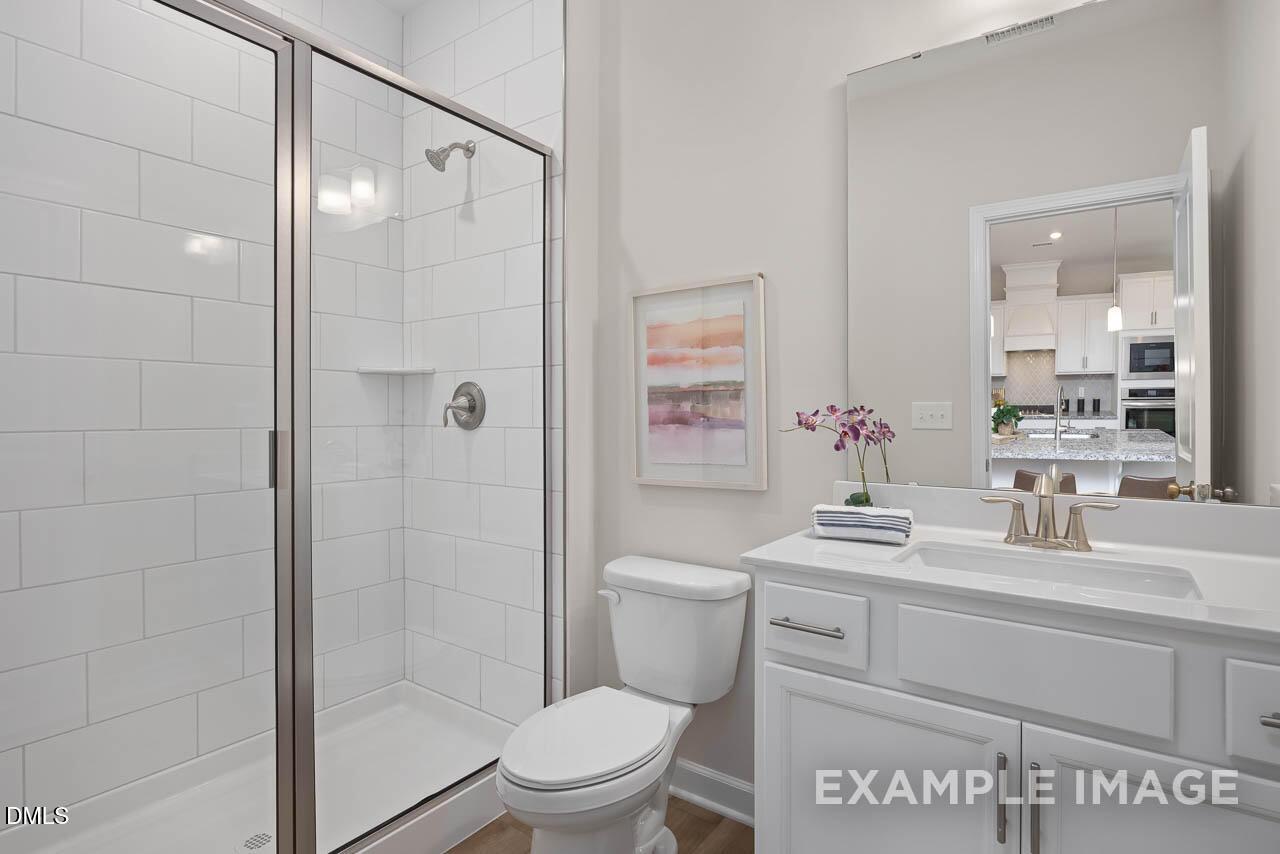 Modern white subway tile shower enclosure and single vanity bathroom in The Willow D floor plan by Davidson Homes, Lillington NC