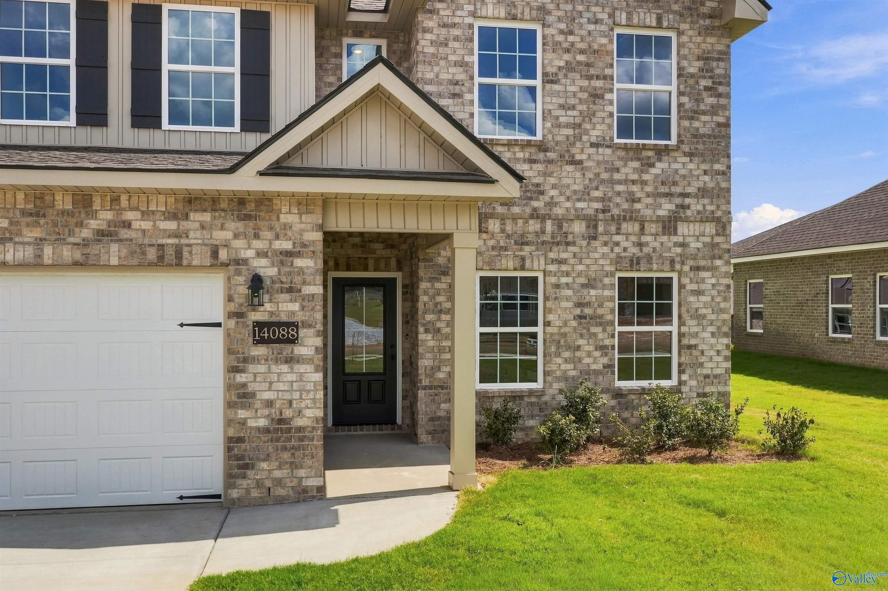 Brick 2-story home exterior with covered porch and 2-car garage in The Meadows, Athens, Alabama by Davidson Homes