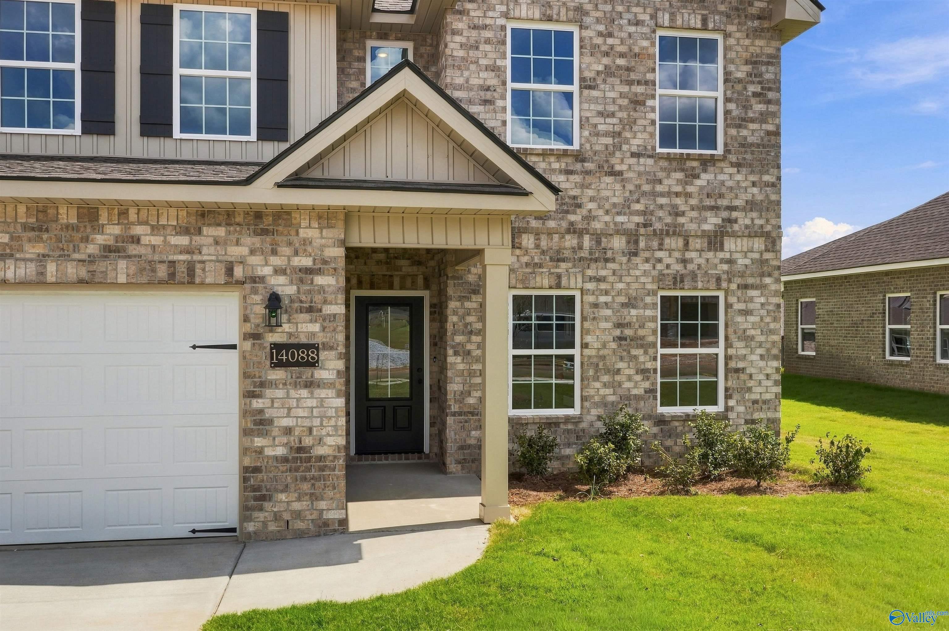 Brick 2-story home exterior with covered porch and 2-car garage in The Meadows, Athens, Alabama by Davidson Homes