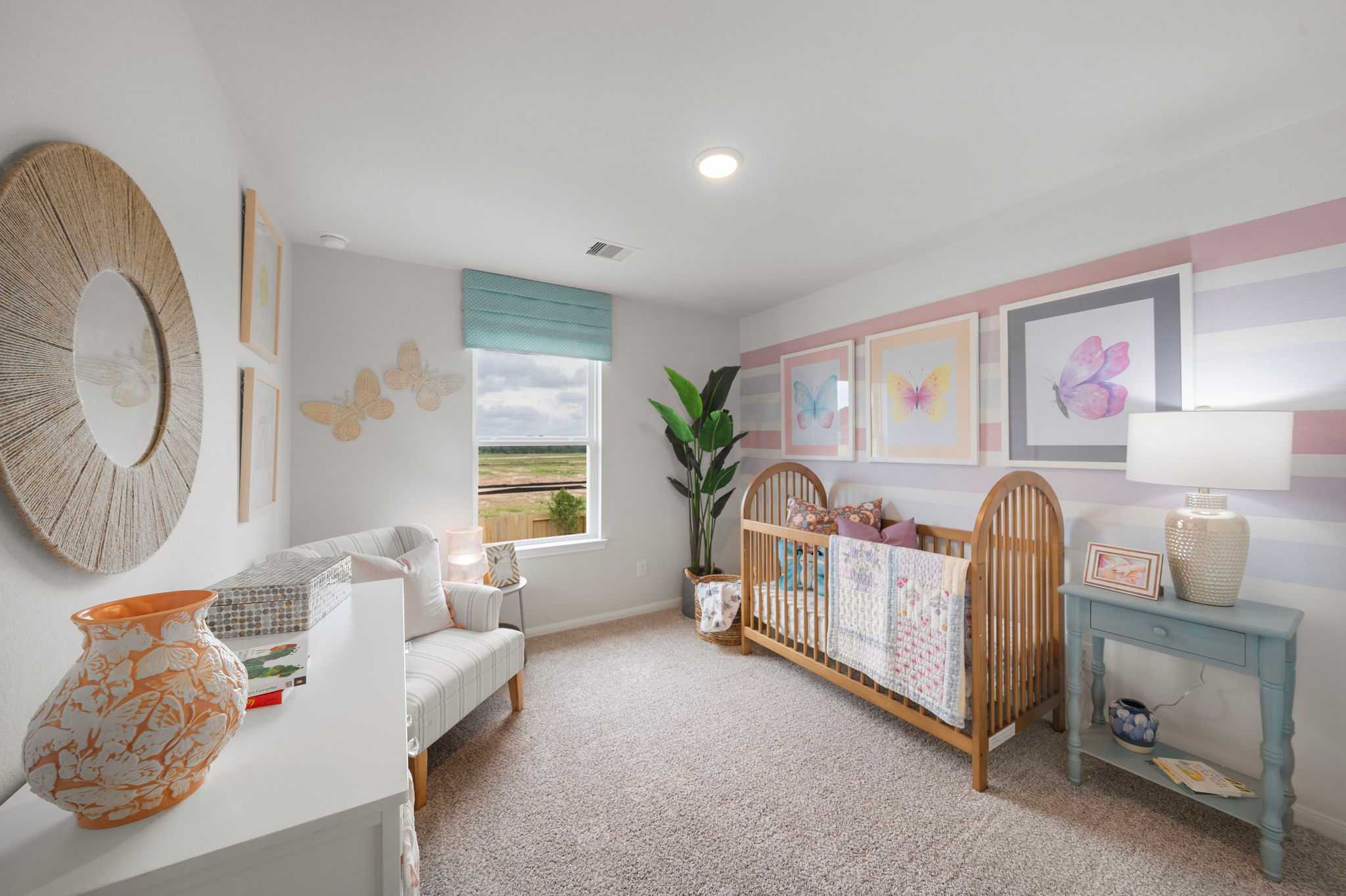 Cozy nursery with wooden crib, butterfly wall art, potted plant, and prairie view at Hill & Dale Ranch in Splendora, Texas