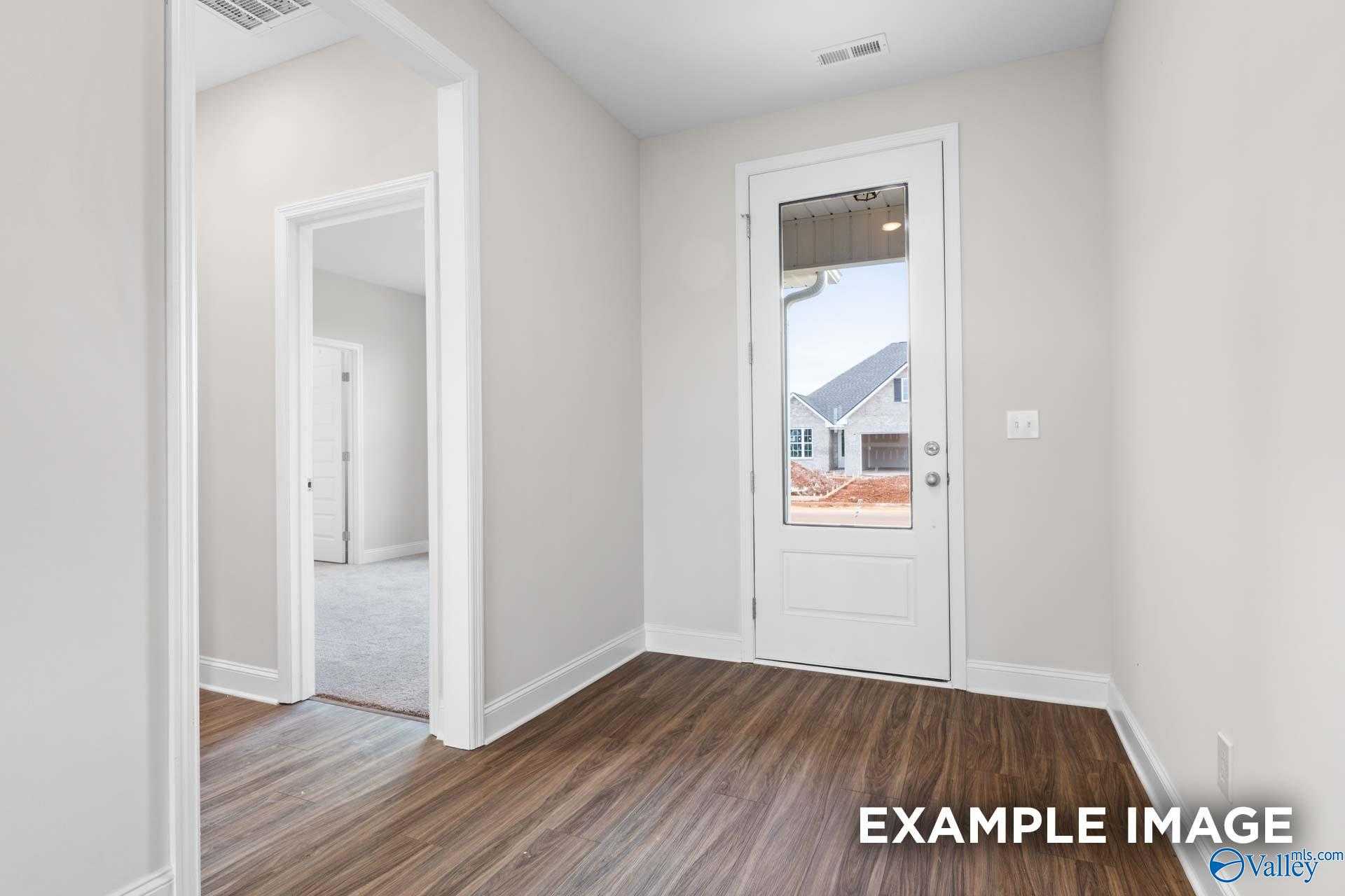 Bright hallway with hardwood floors, white glass door to backyard, and open doorway in The Montgomery 3-bedroom home, Athens AL