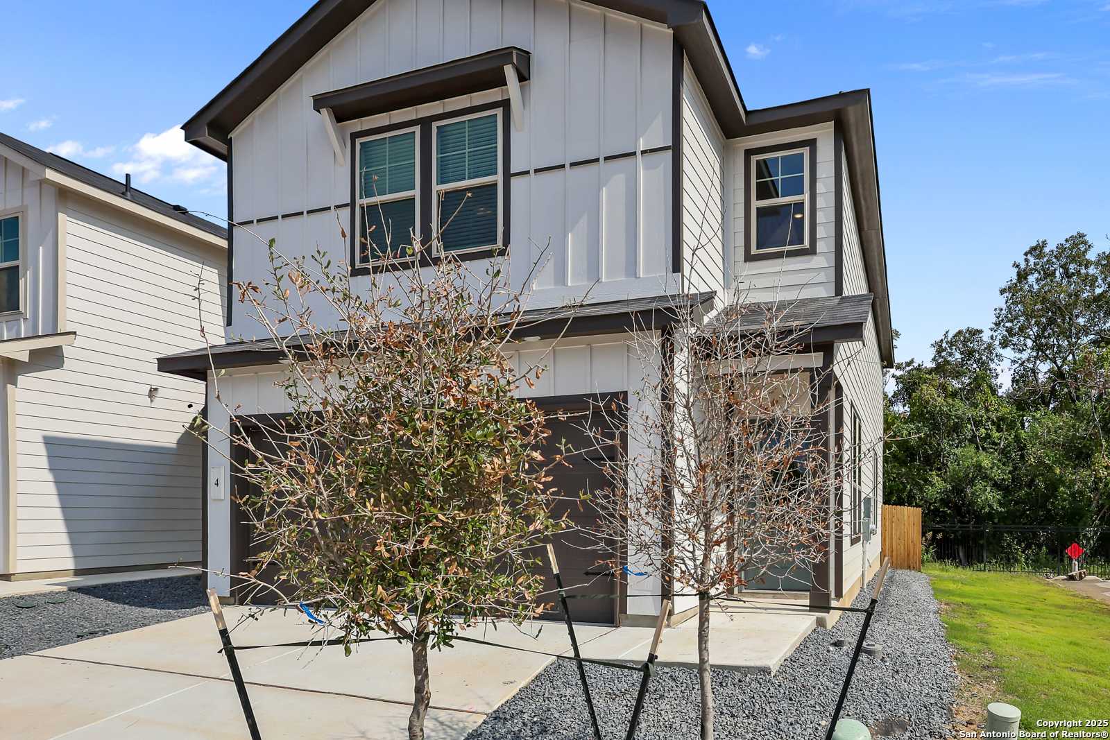 Two-story Florence C home by Davidson Homes in Cedar Heights, San Antonio, Texas, with white shiplap exterior, two-car garage, and front yard trees