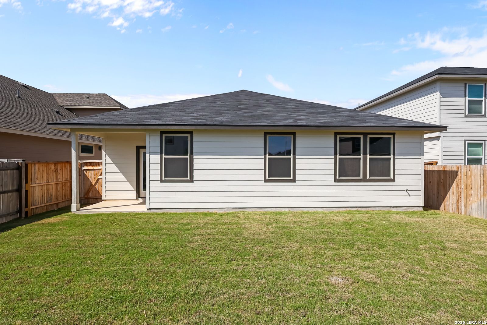 Rear view of The Daphne H single-story home with covered patio, attached garage, and lush green backyard in Hannah Heights, Seguin, Texas