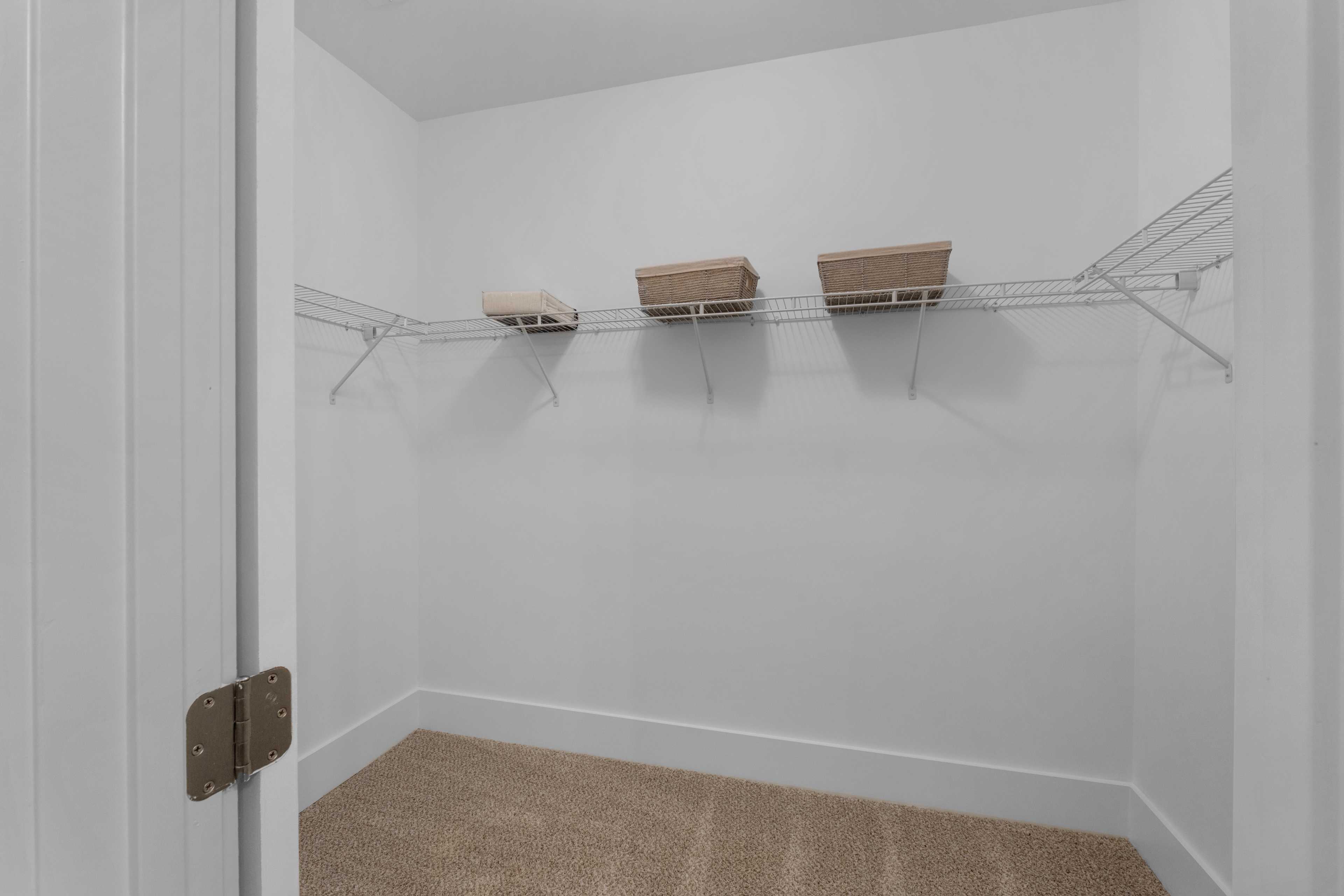 Spacious walk-in closet with wire shelving and beige baskets at Hollon Meadow in Decatur, Alabama by Davidson Homes