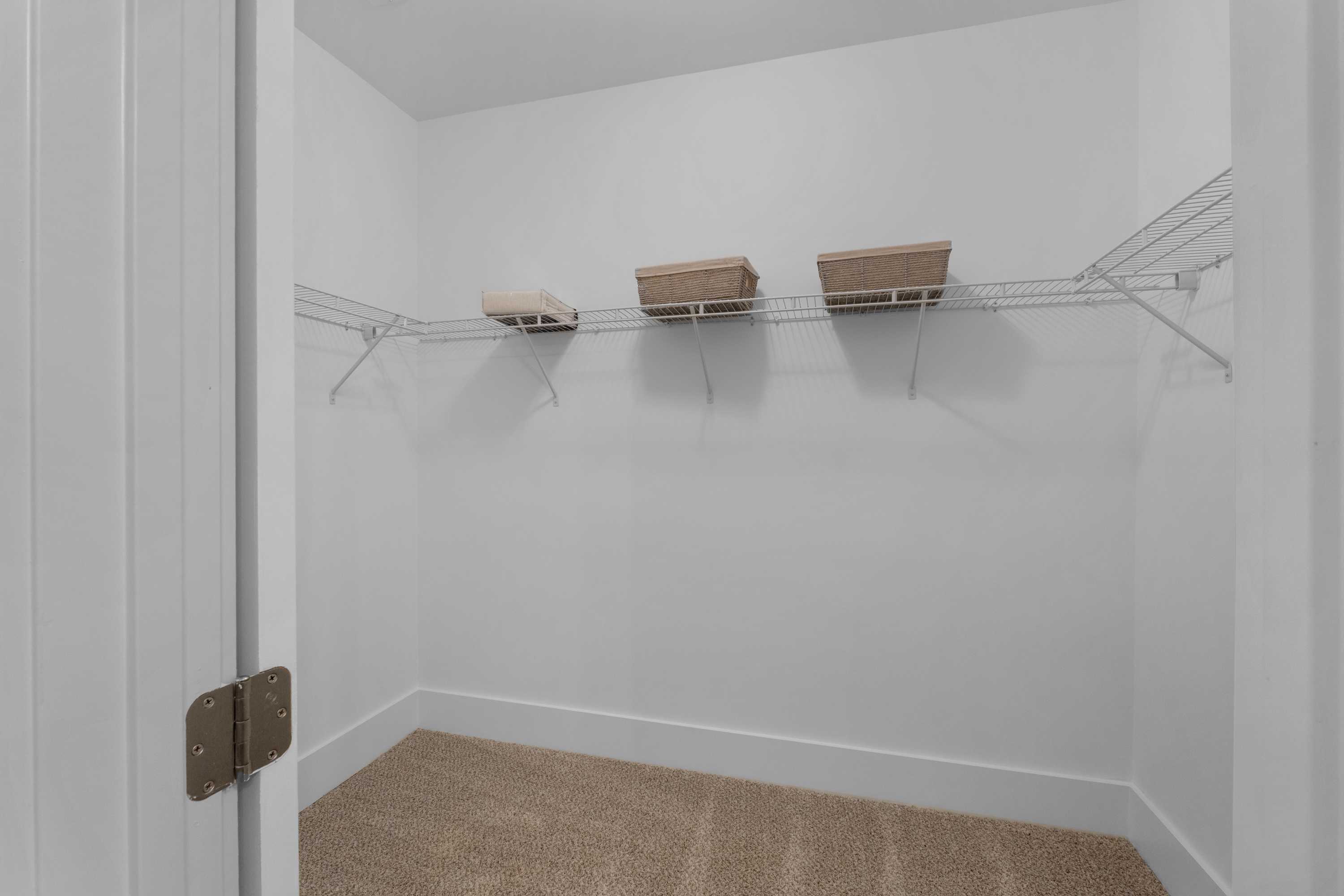 Spacious walk-in closet with wire shelving and beige baskets at Hollon Meadow in Decatur, Alabama by Davidson Homes