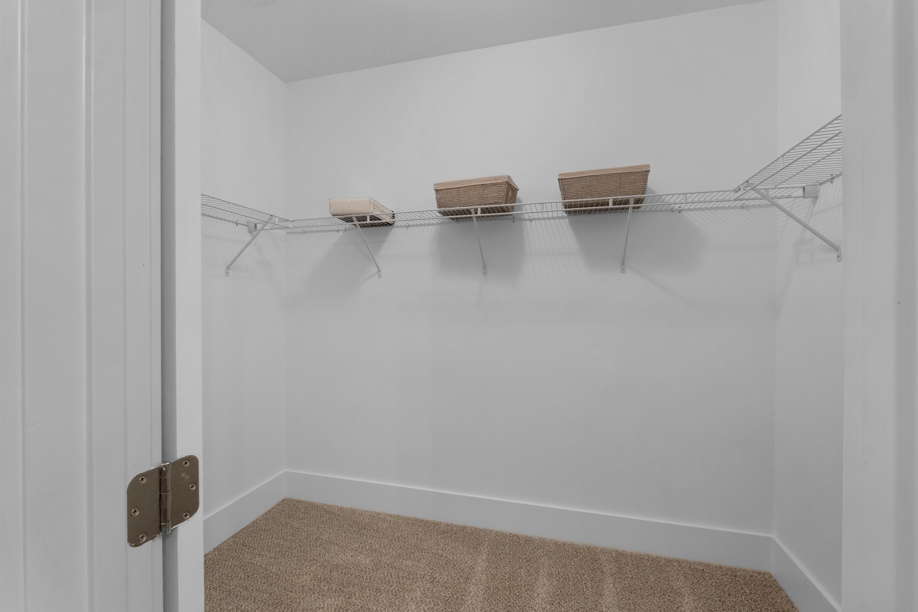 Spacious walk-in closet with wire shelving and beige baskets at Hollon Meadow in Decatur, Alabama by Davidson Homes