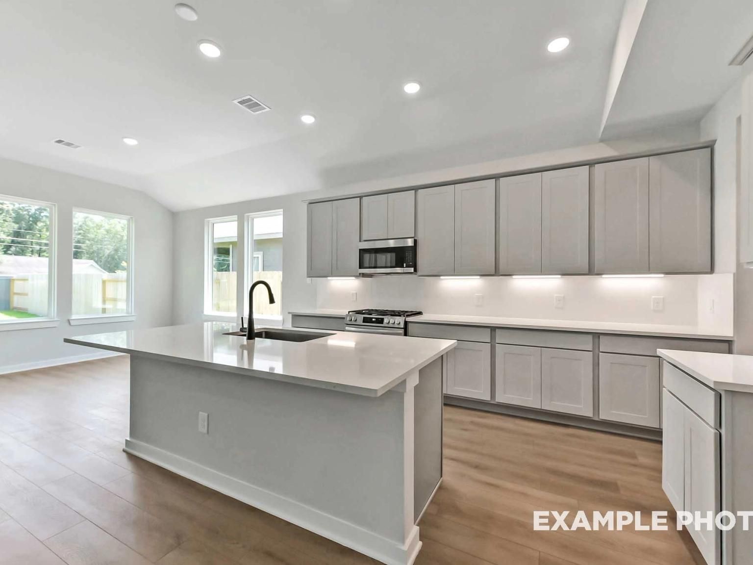 Modern kitchen with white quartz island, gray cabinets, and stainless appliances in The Sequoia C at Sundance Cove, Crosby.