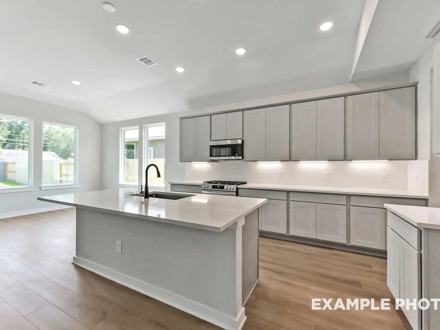 Modern kitchen with white quartz island, gray cabinets, and stainless appliances in The Sequoia C at Sundance Cove, Crosby.