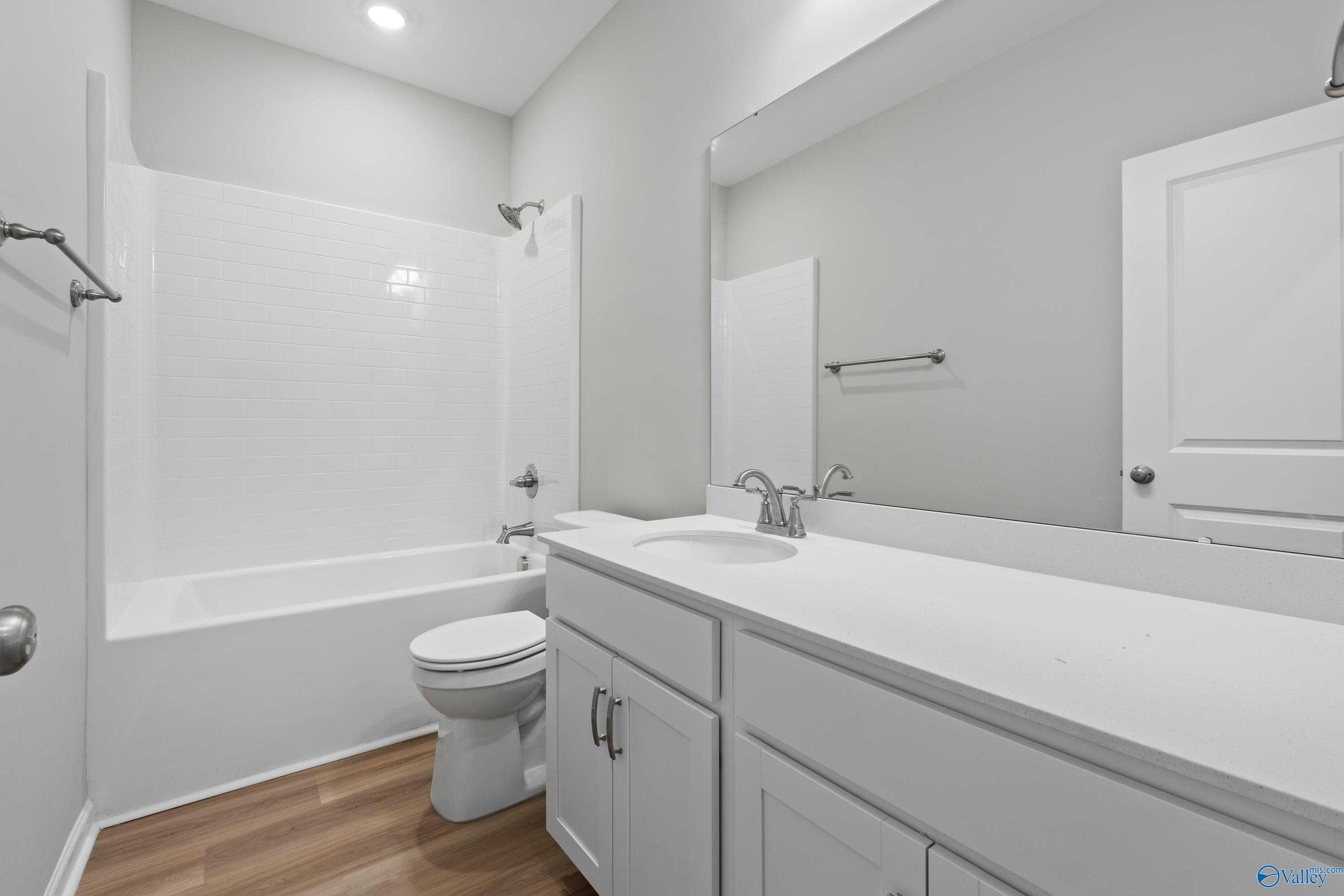 Bright guest bathroom featuring white tub-shower combo, double-sink vanity, and light wood floors in Davidson Homes The Polaris, Fayetteville, TN