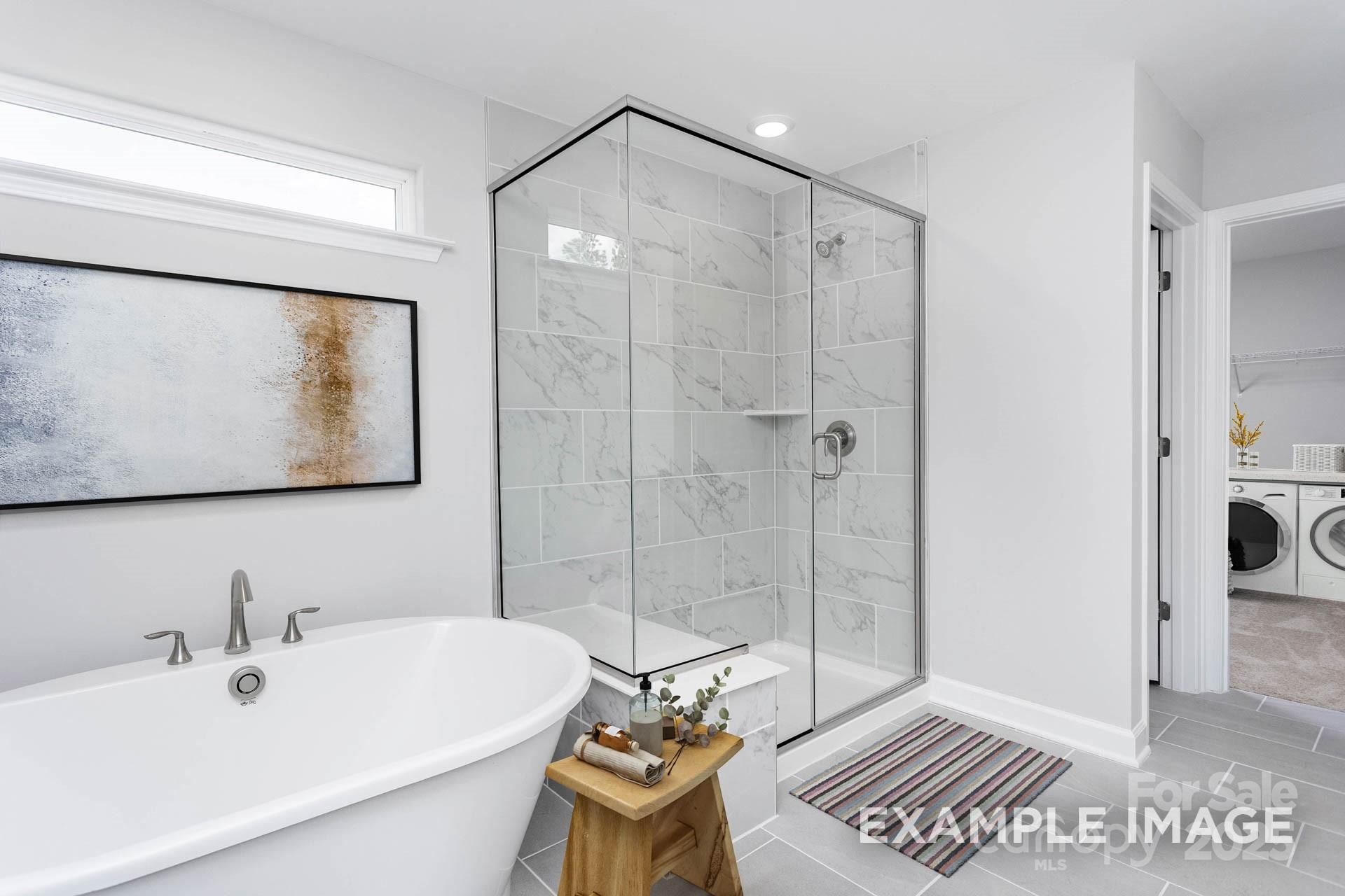 Elegant master bathroom with freestanding tub, marble glass shower and laundry nook in Davidson Homes The Hemlock A, Belmont NC