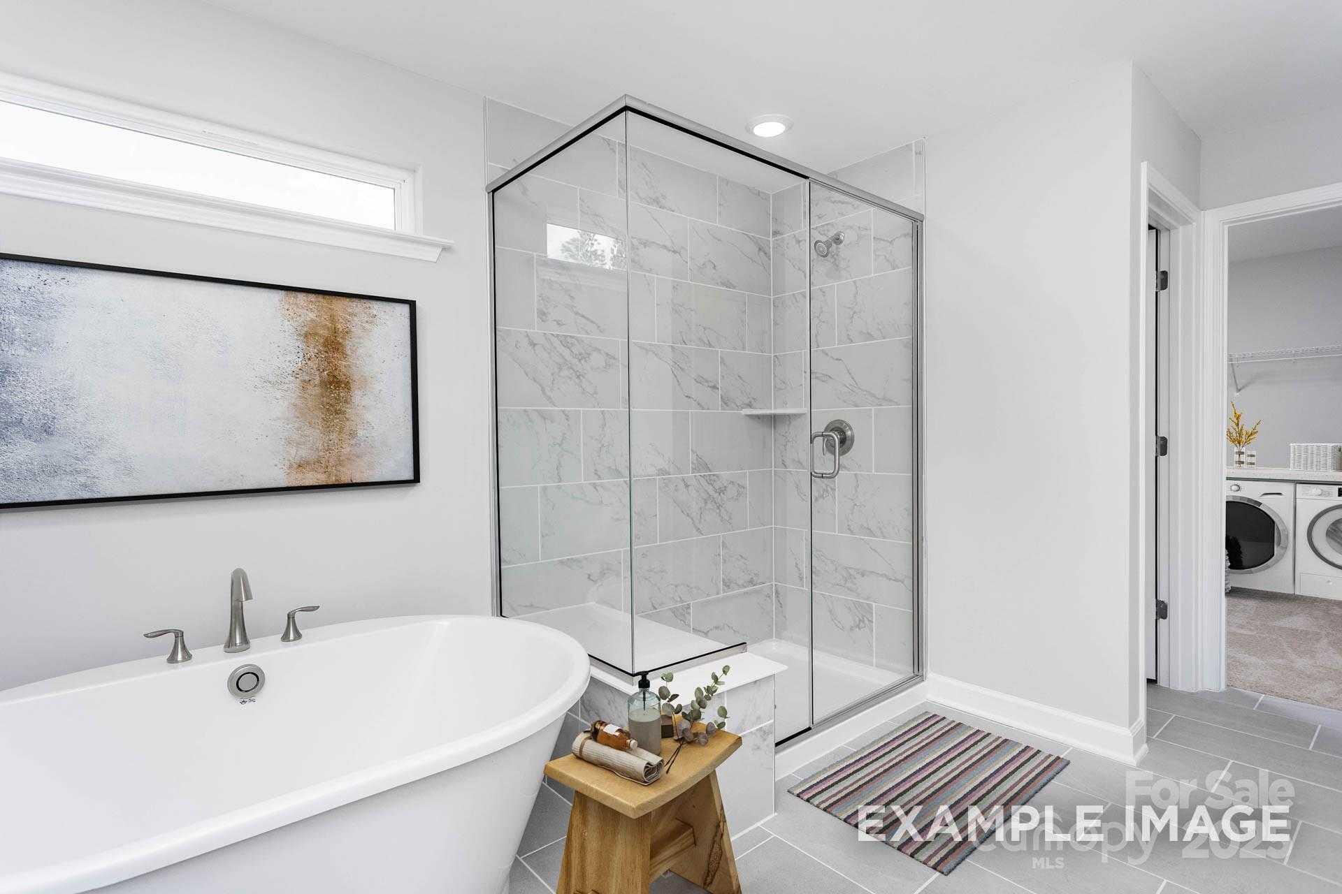 Elegant master bathroom with freestanding tub, glass shower, and marble tiles in Davidson Homes The Hemlock A, Belmont, NC