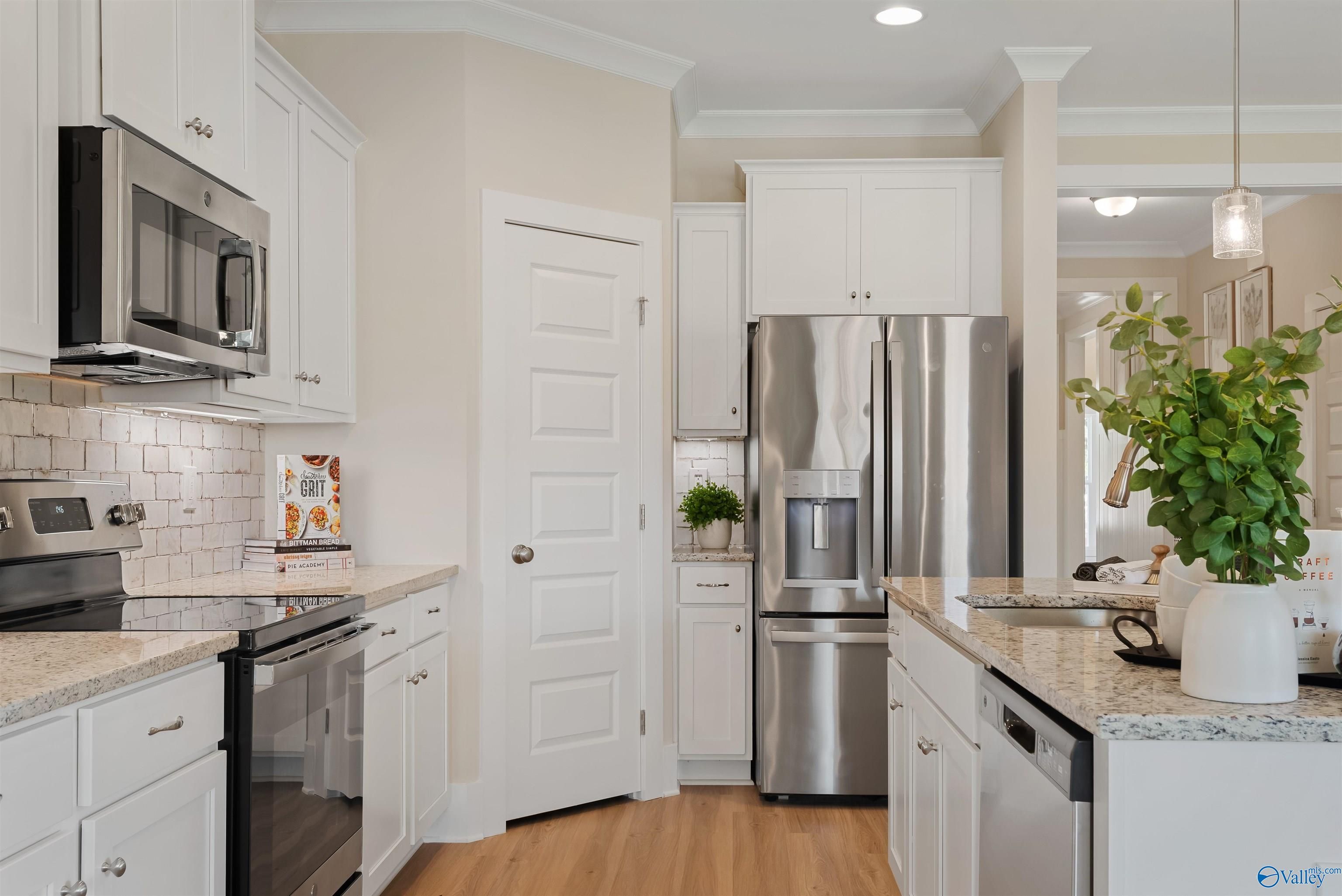 Modern kitchen with white shaker cabinets, stainless steel appliances, granite countertops in Davidson Homes The Everett, New Market, Alabama