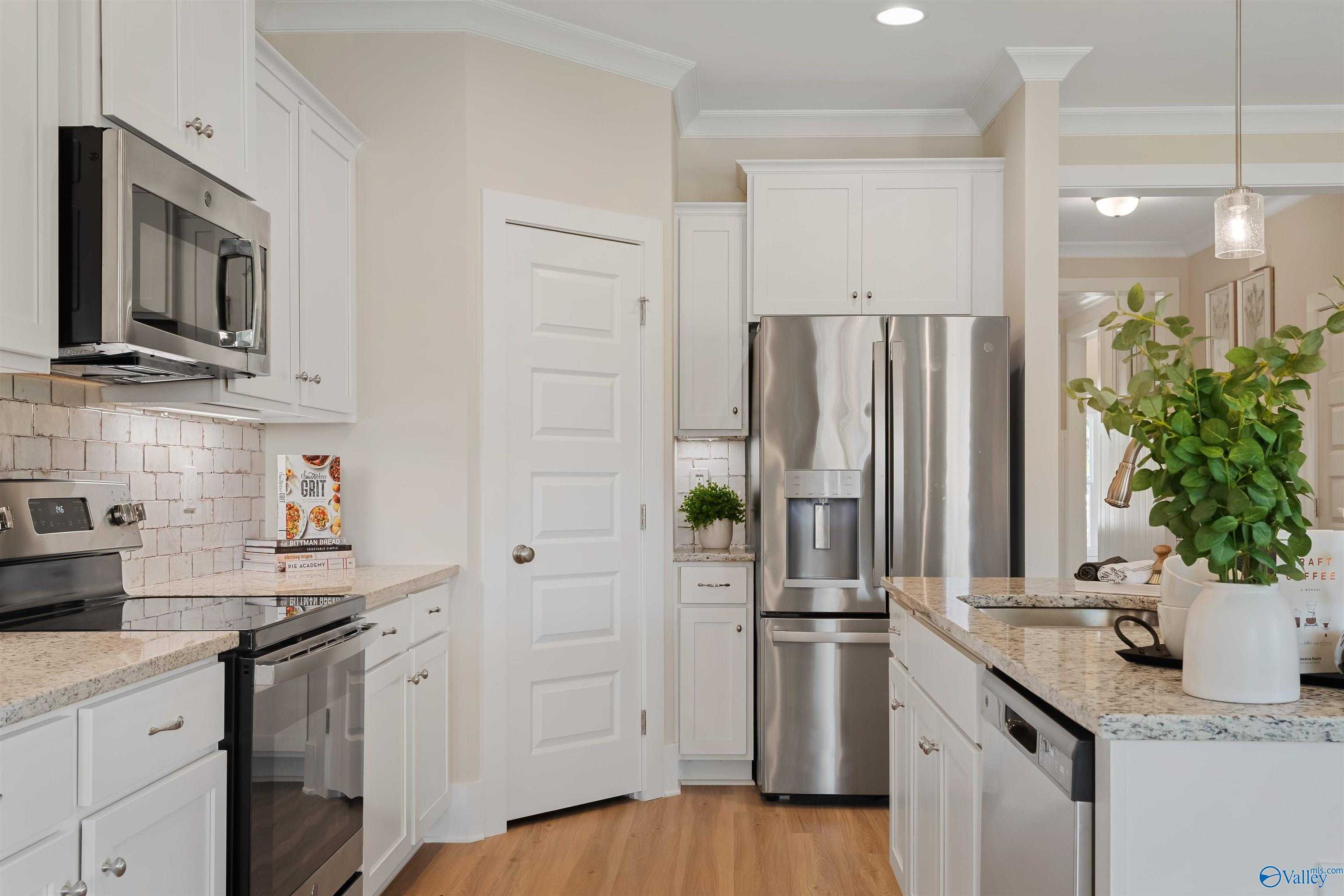 Modern kitchen with white shaker cabinets, stainless steel appliances, granite countertops in Davidson Homes The Everett, New Market, Alabama
