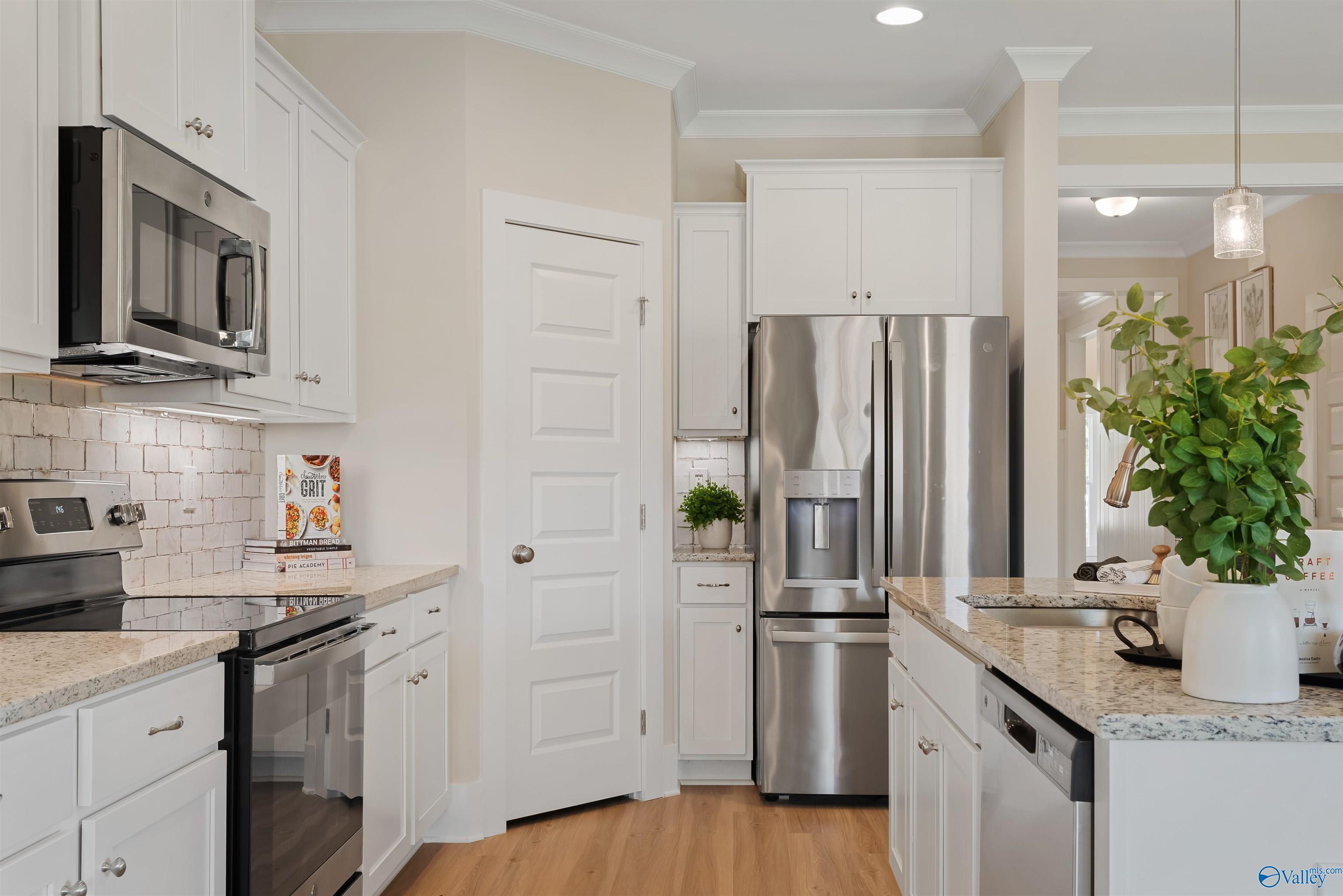 Modern kitchen with white shaker cabinets, stainless steel appliances, granite countertops in Davidson Homes The Everett, New Market, Alabama
