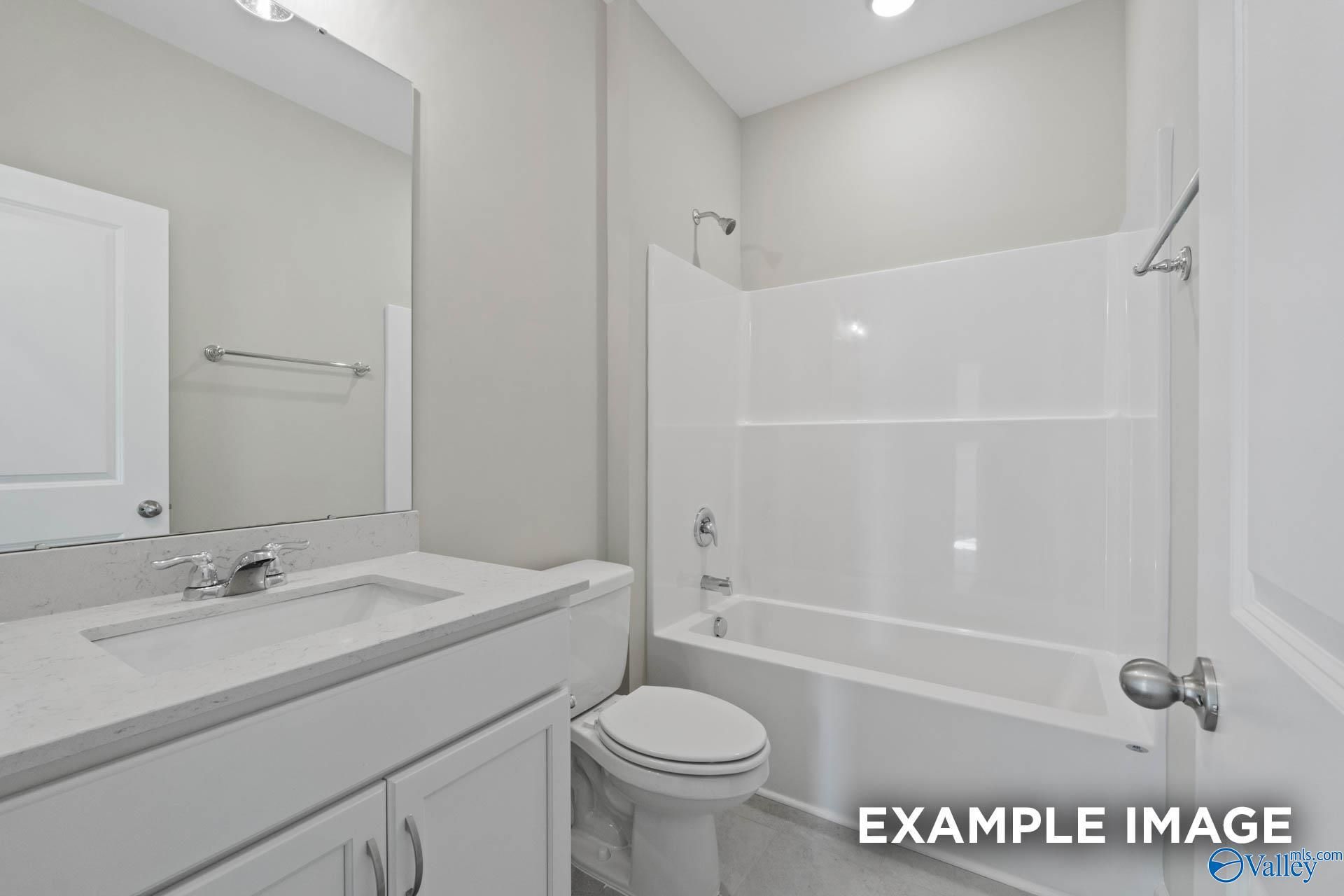 Modern white bathroom with tub-shower combo, single vanity sink, and toilet in Davidson Homes The Montgomery B, Hartselle, Alabama