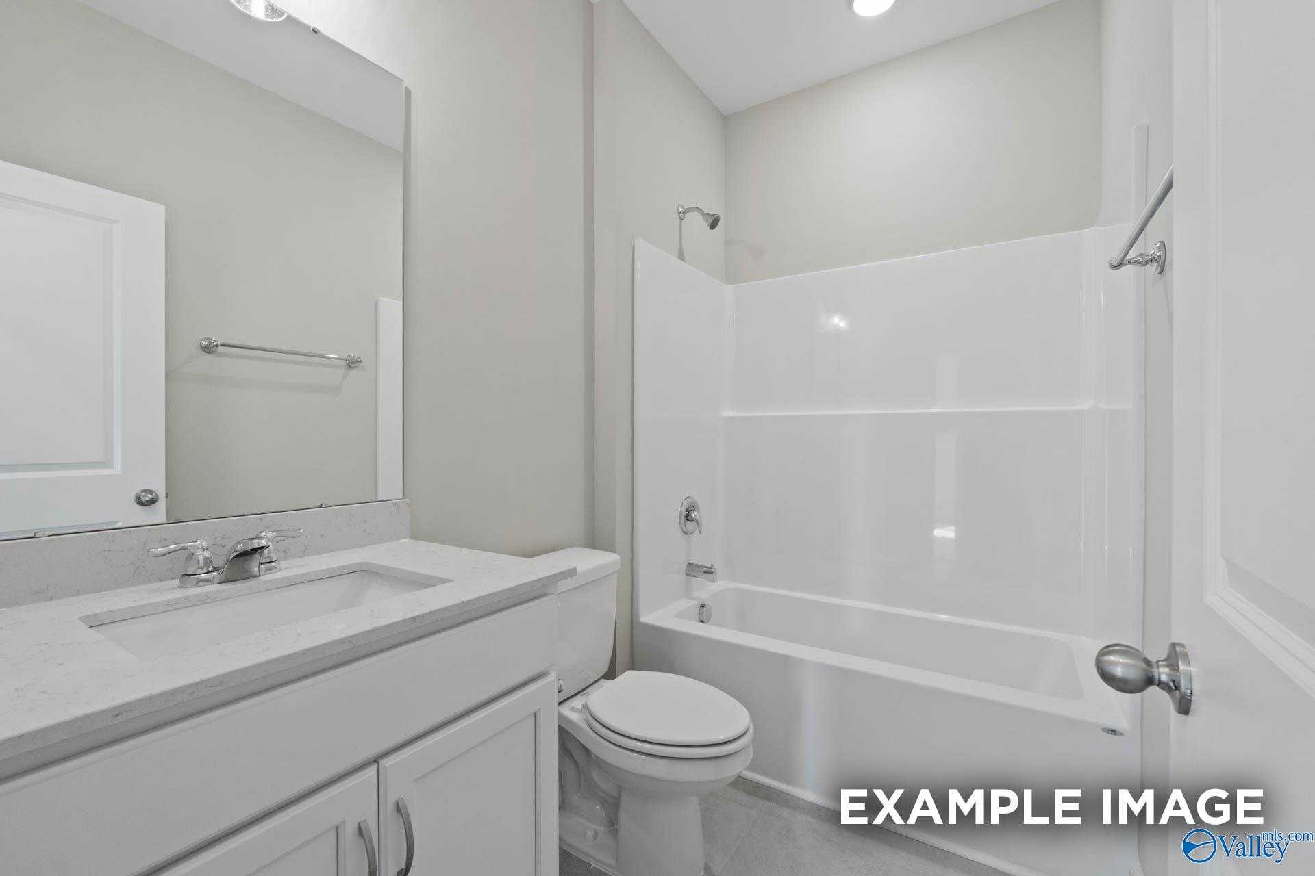 Modern white bathroom with tub-shower combo, single vanity sink, and toilet in Davidson Homes The Montgomery B, Hartselle, Alabama
