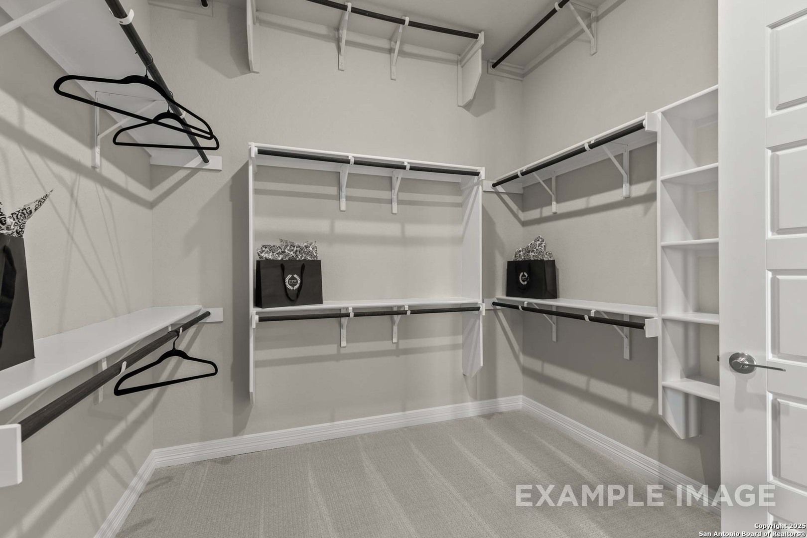 Spacious walk-in closet with built-in white shelving, hanging rods, and storage in Davidson Homes Summerlin B, Castroville, Texas