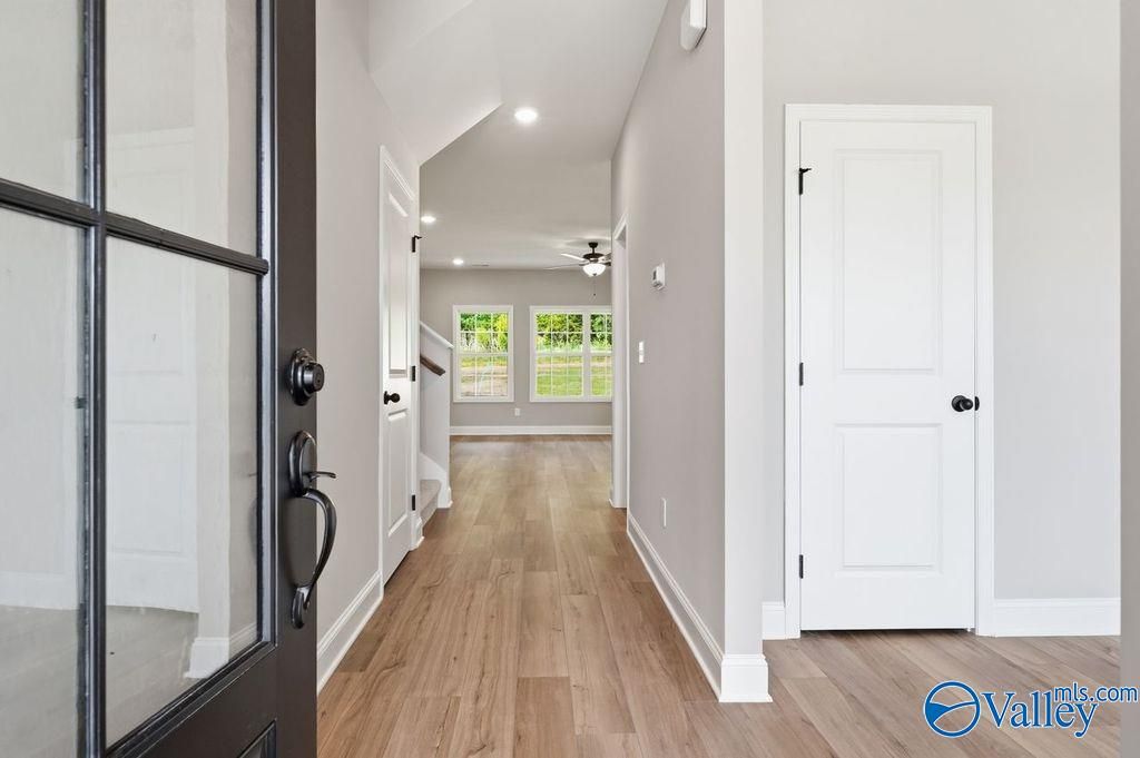 Inviting foyer with glass front door, hardwood floors, and backyard view through windows in Davidson Homes The Rockford, Hartselle, Alabama
