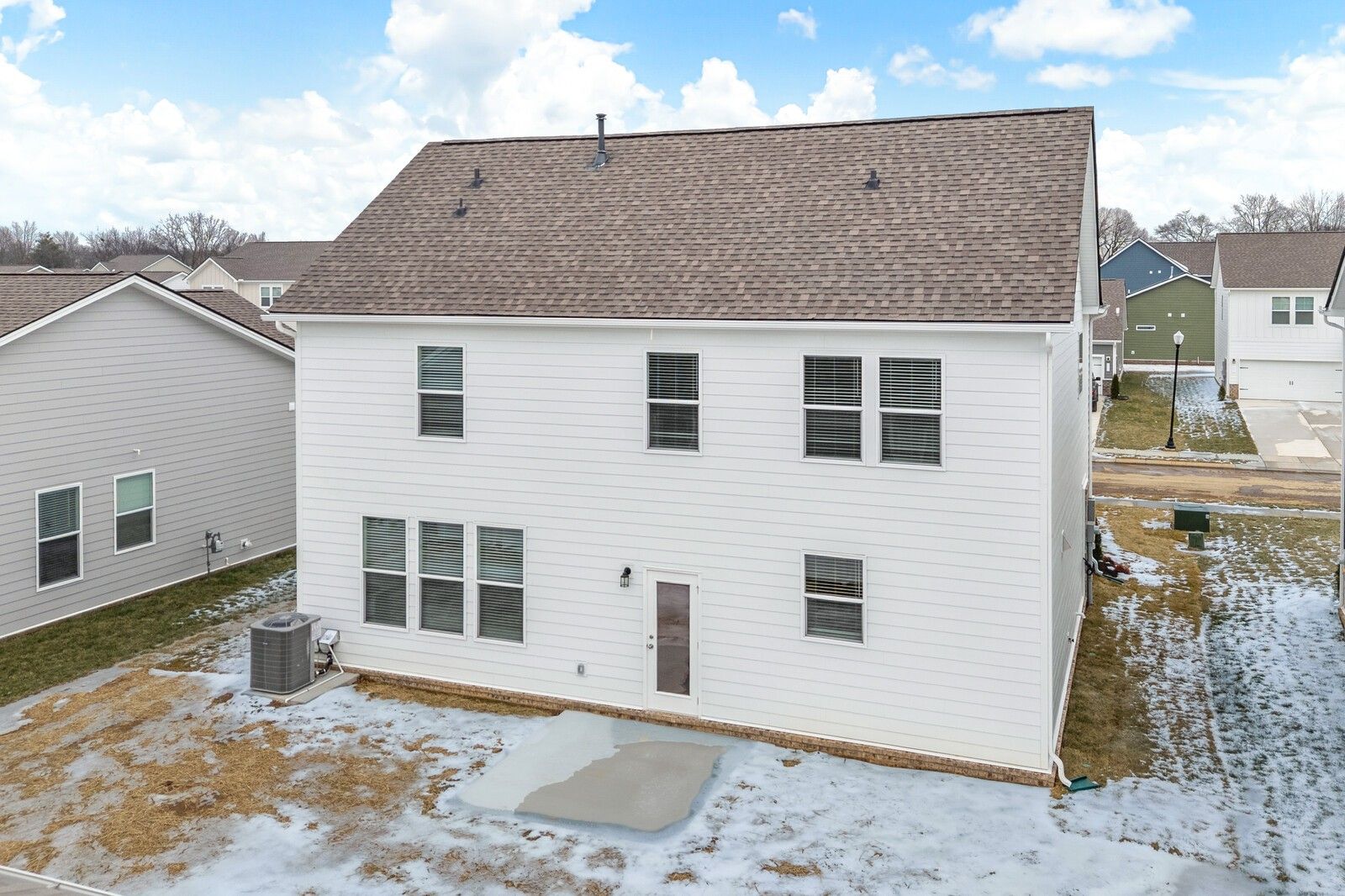 Two-story 3-bedroom home rear with white siding, brown roof, covered patio, and snowy yard in Davidson Homes Gordon C, Sage Farms