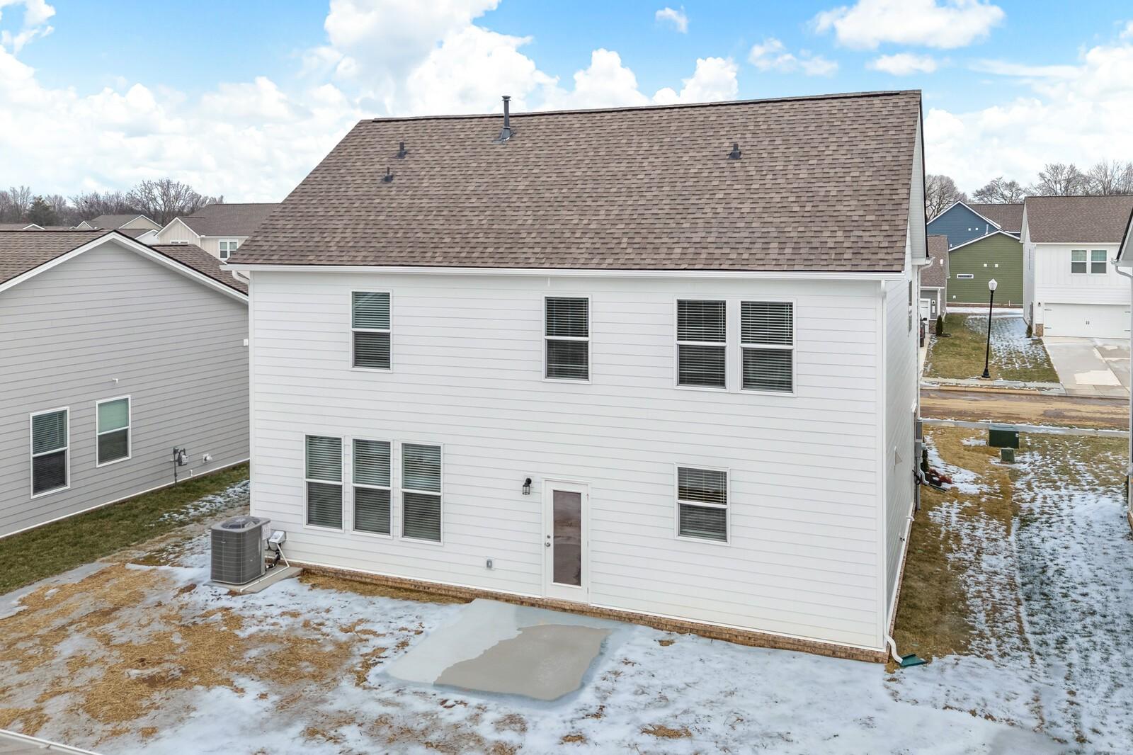 Two-story 3-bedroom home rear with white siding, brown roof, covered patio, and snowy yard in Davidson Homes Gordon C, Sage Farms