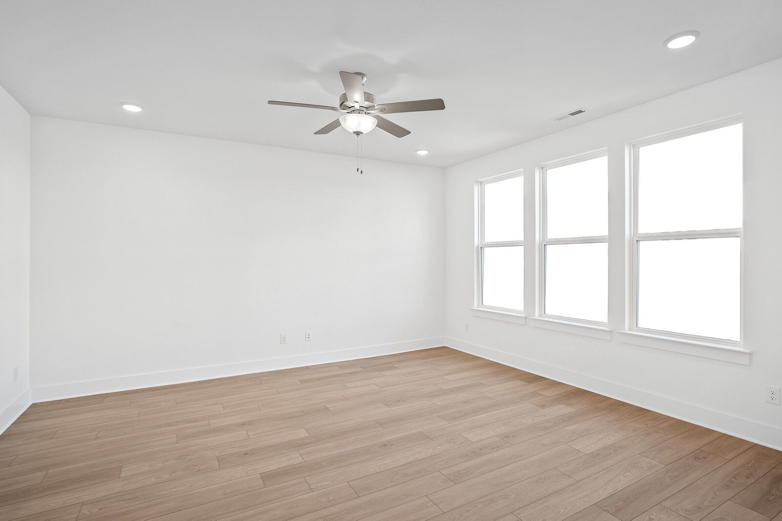 Bright bedroom with hardwood floors, three large windows, and ceiling fan in Davidson Homes The Logan C, Gallatin, Tennessee