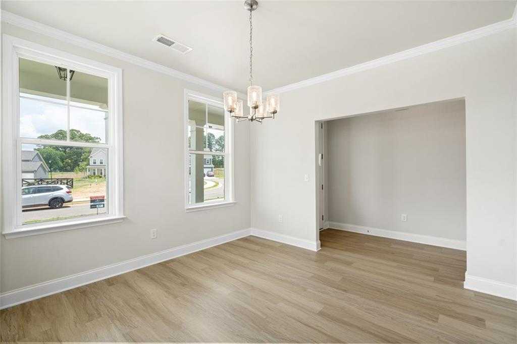 Bright living room with large windows, crystal chandelier, hardwood floors in Davidson Homes The Willow B, Hoschton, GA