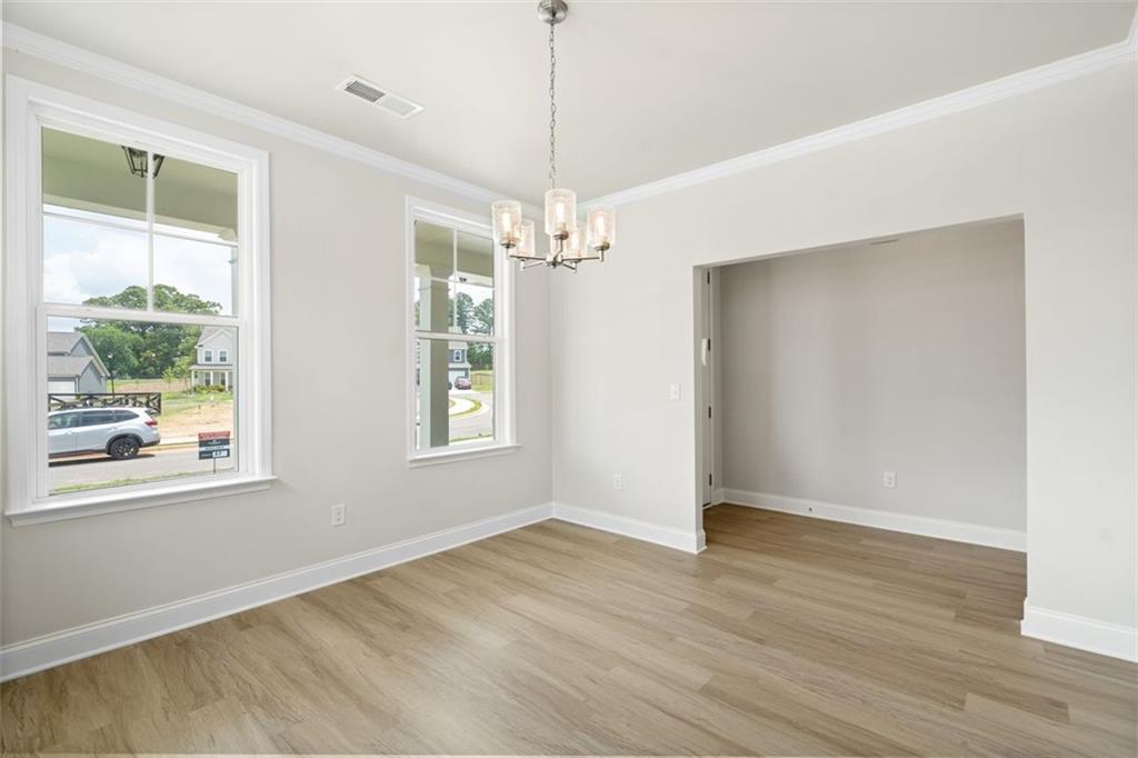 Bright living room with large windows, crystal chandelier, hardwood floors in Davidson Homes The Willow B, Hoschton, GA