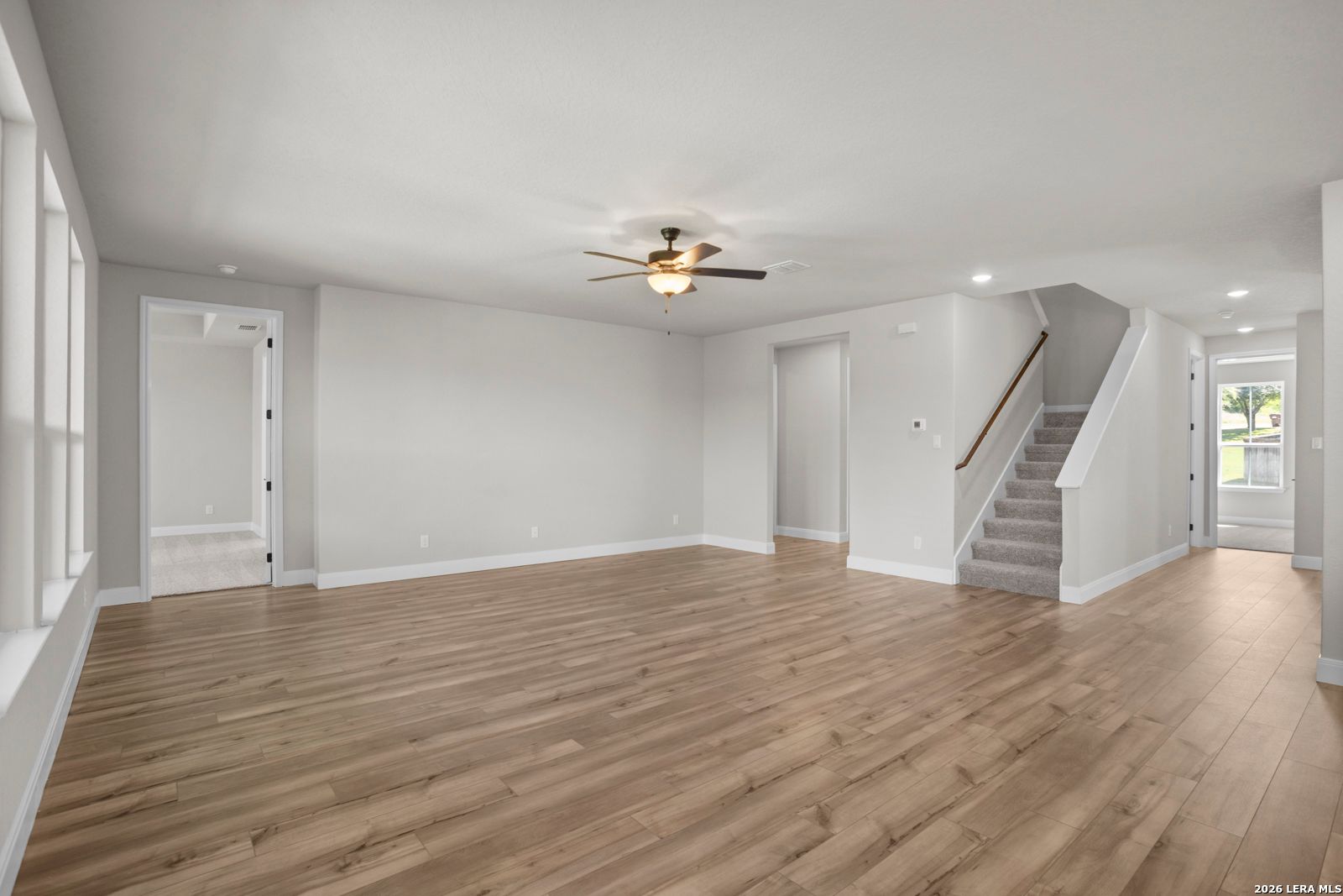 Spacious living room with wood-style flooring and staircase in The Jennings G floor plan at Ladera, San Antonio, Texas.
