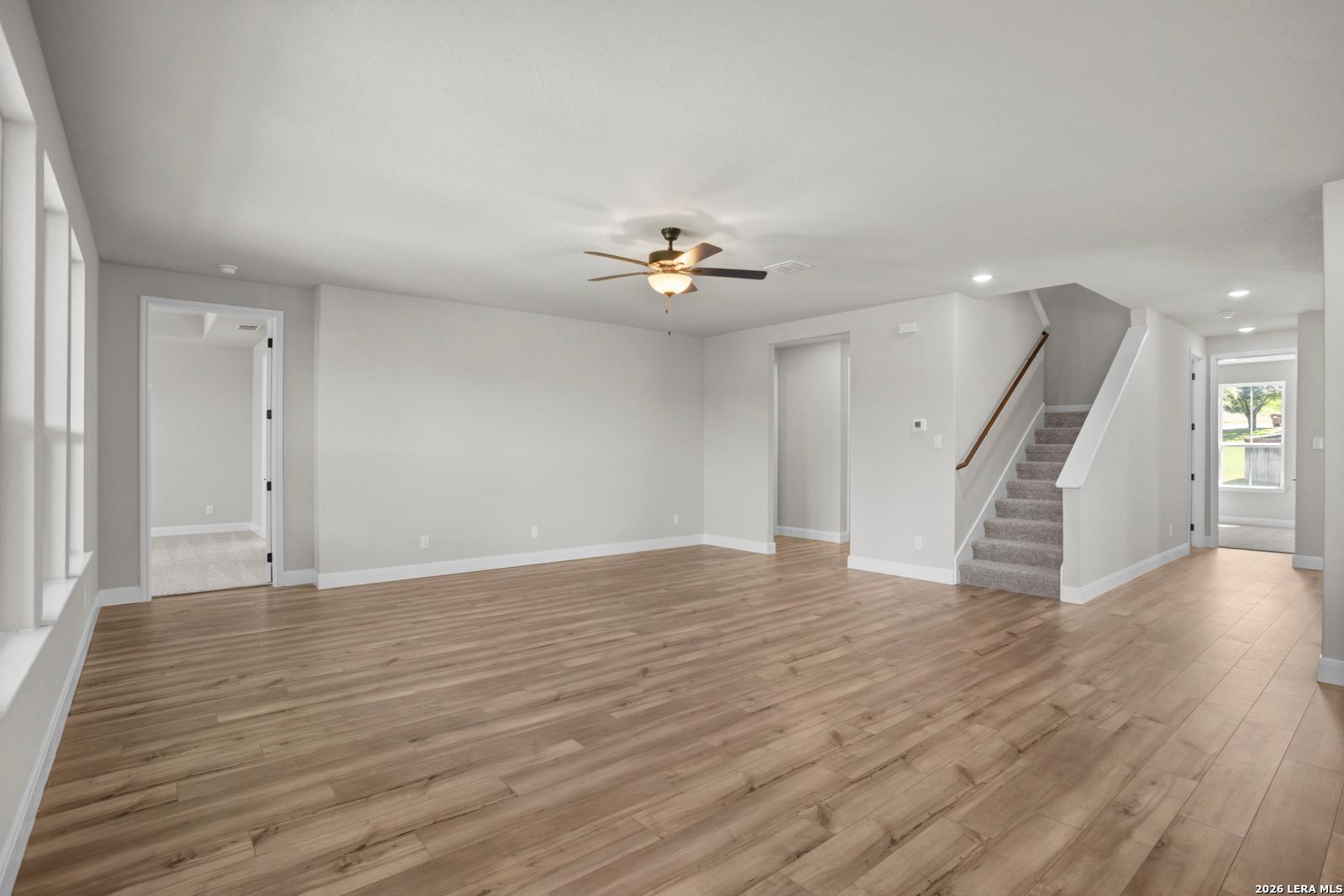 Spacious living room with wood-style flooring and staircase in The Jennings G floor plan at Ladera, San Antonio, Texas.