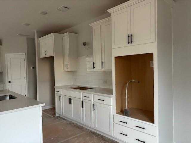 Modern white shaker kitchen with island sink, subway tile backsplash, and open shelving in Davidson Homes The Rabun C, Winder, GA