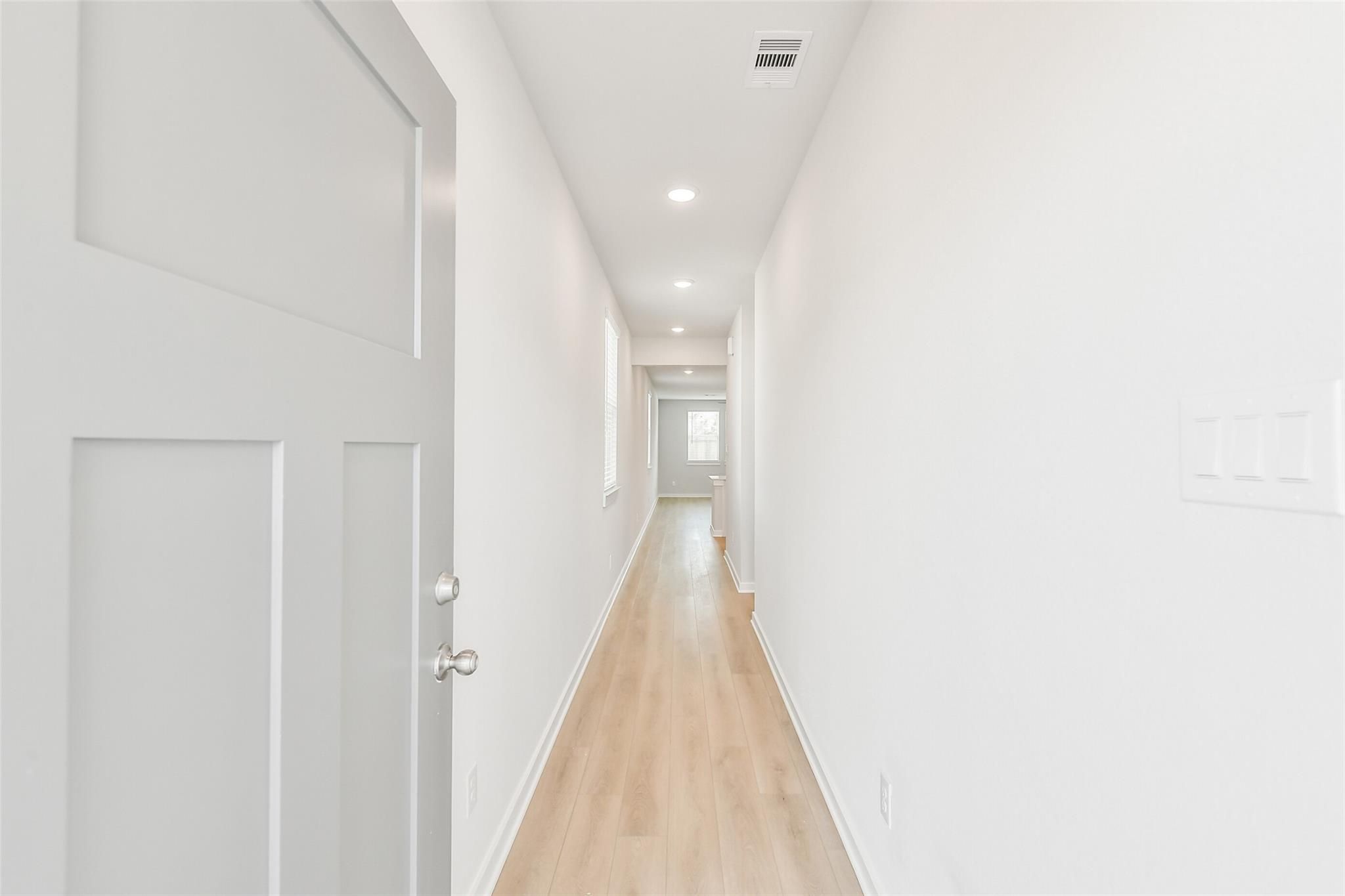 Bright hallway with open door, hardwood floors, and recessed lights in Davidson Homes The Colorado F, Cleveland, Texas