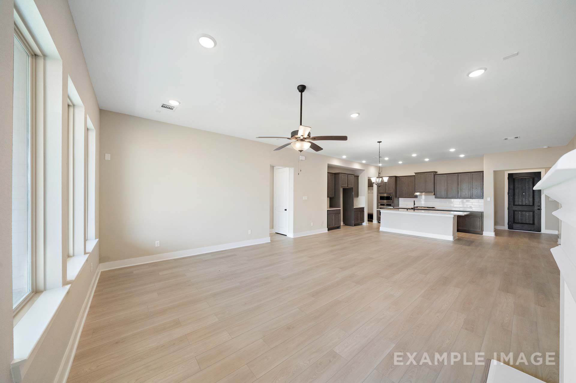 Open-concept living area and kitchen in The Elizabeth by Davidson Homes, featuring dark cabinetry and wood-look flooring