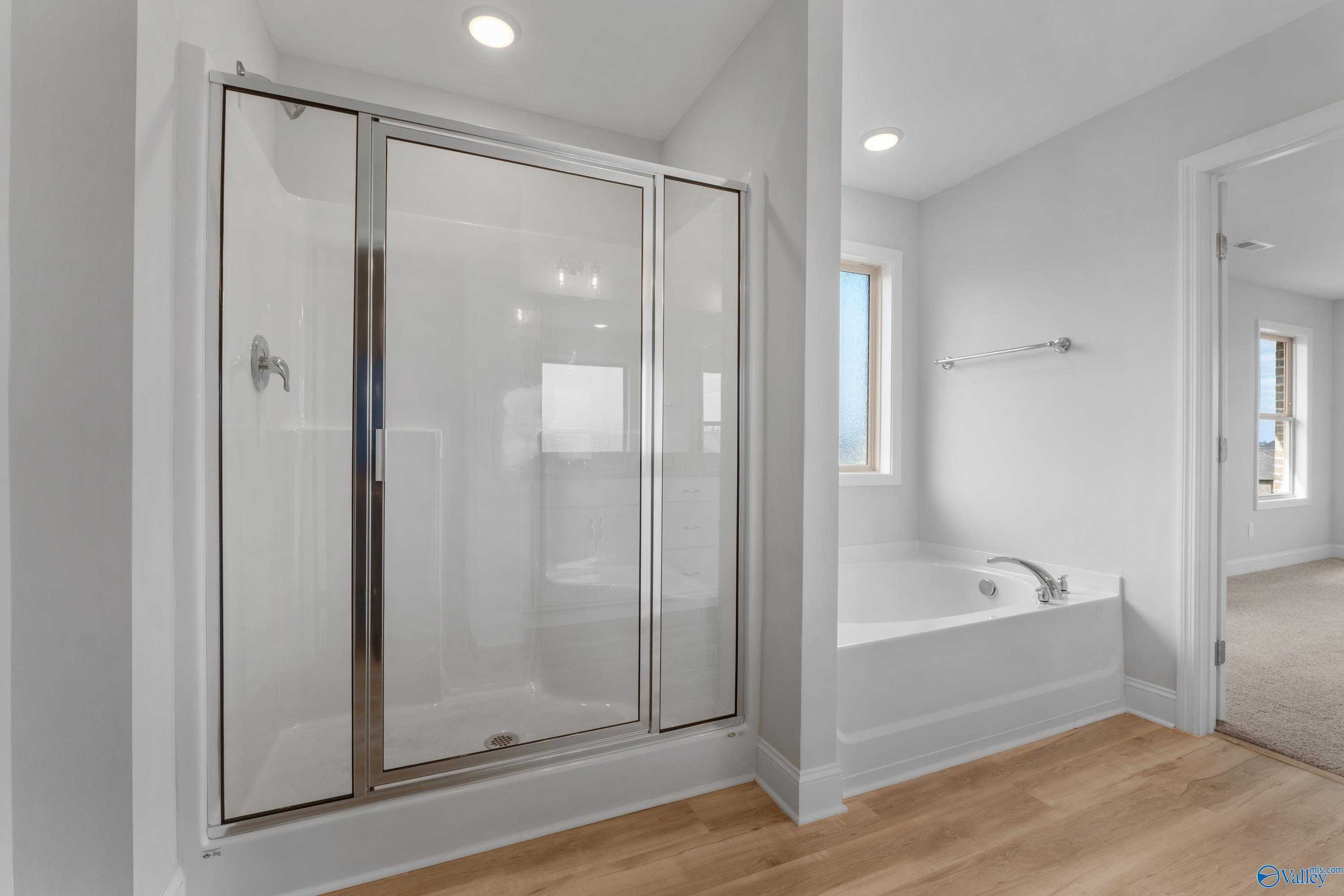 Modern master bathroom with frameless glass shower, deep soaking tub, and recessed lighting in Davidson Homes Chelsea C, Harvest AL