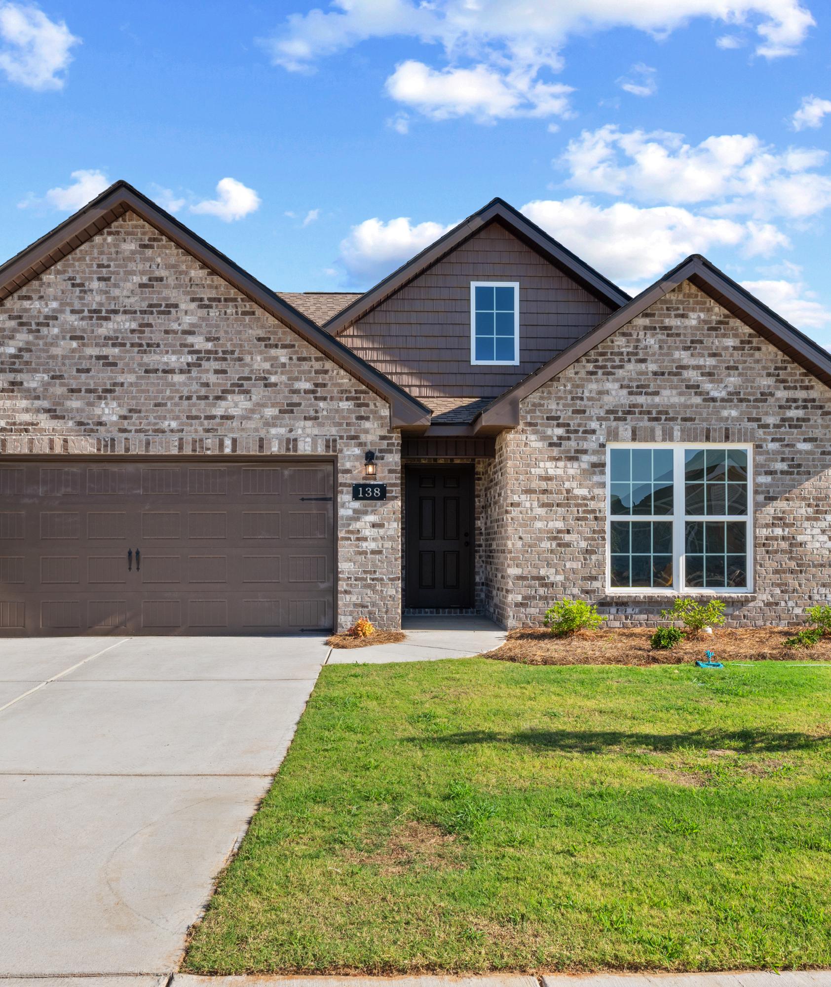 Brick exterior of a Davidson Homes house at Hitching Post in Madison, Alabama, featuring a two-car garage and front yard.