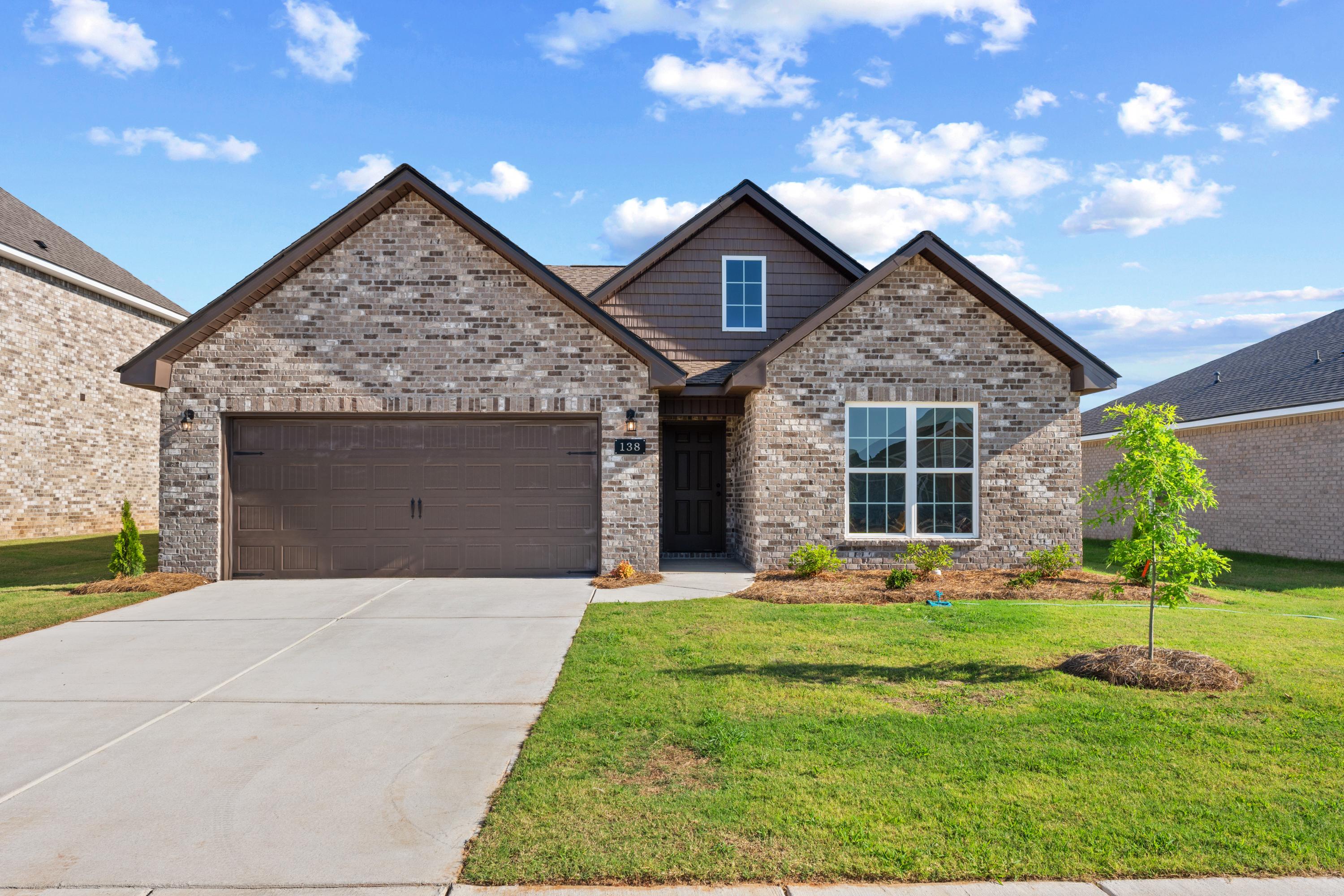 Brick exterior of a Davidson Homes house at Hitching Post in Madison, Alabama, featuring a two-car garage and front yard.
