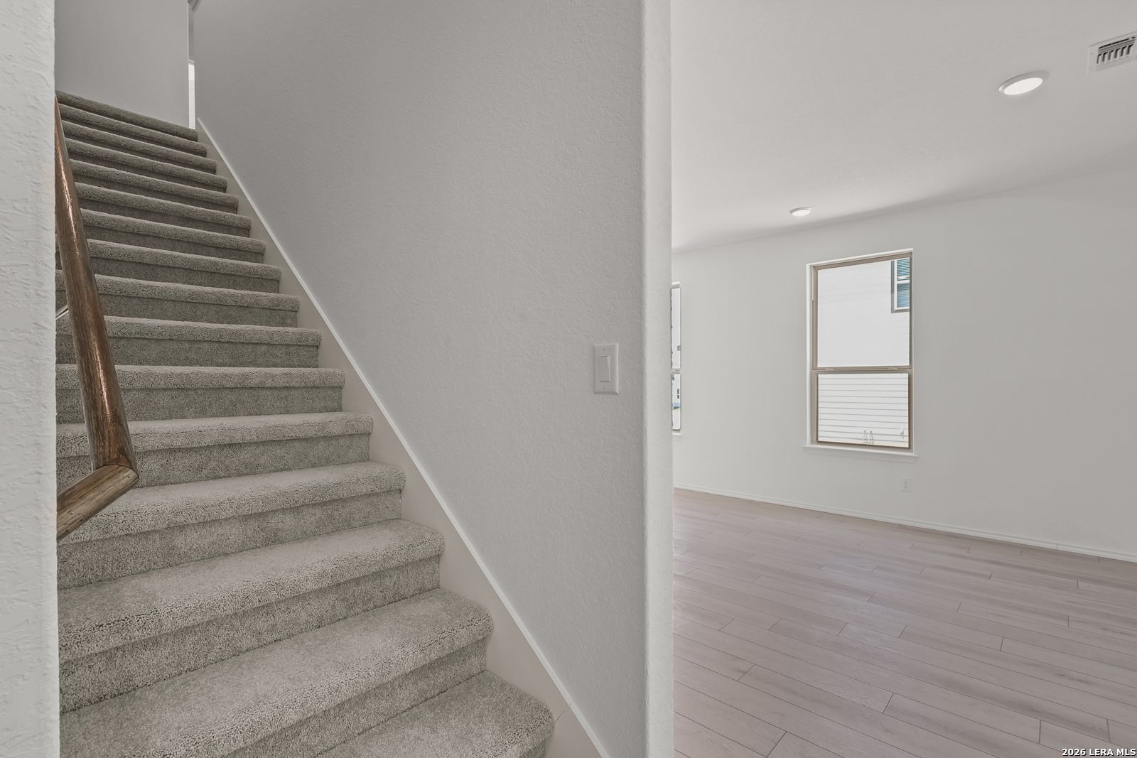 Carpeted staircase with wooden handrail leading to bright living area in The Gillian C floor plan, Meadows at Oak Creek.