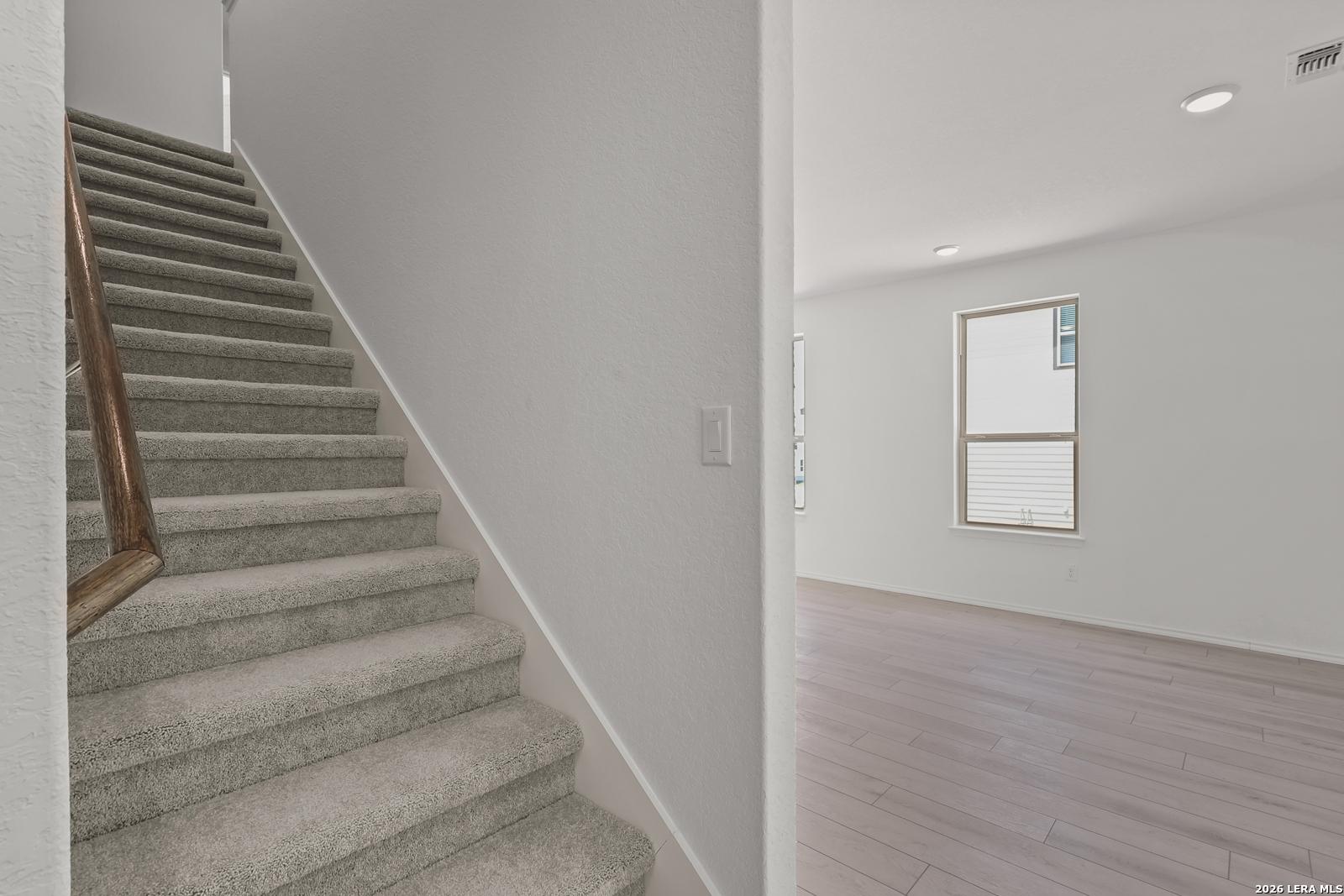 Carpeted staircase with wooden handrail leading to bright living area in The Gillian C floor plan, Meadows at Oak Creek.