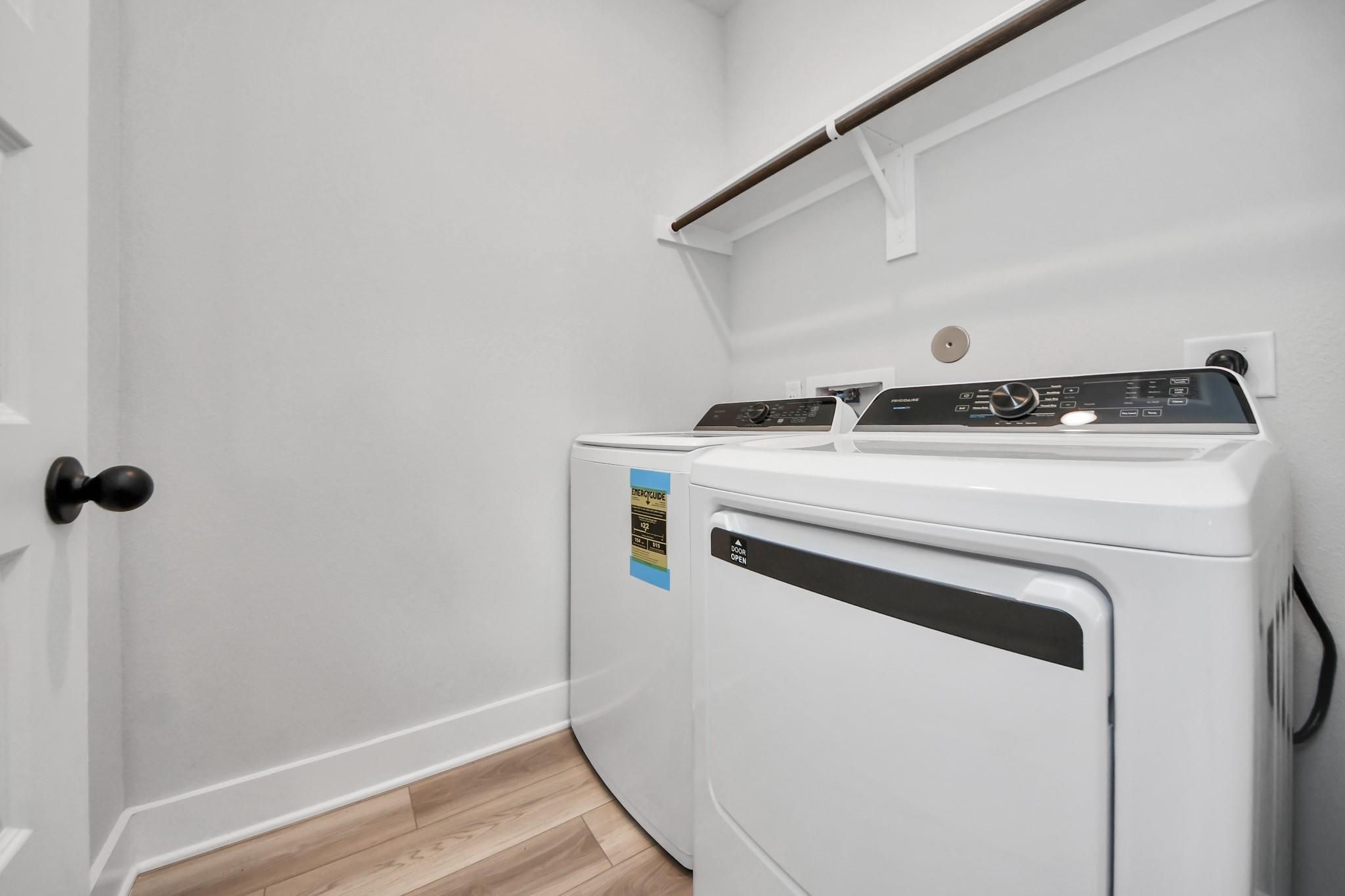 Laundry room with white washer and dryer and storage shelving in The Laguna C floor plan by Davidson Homes in Katy, Texas.