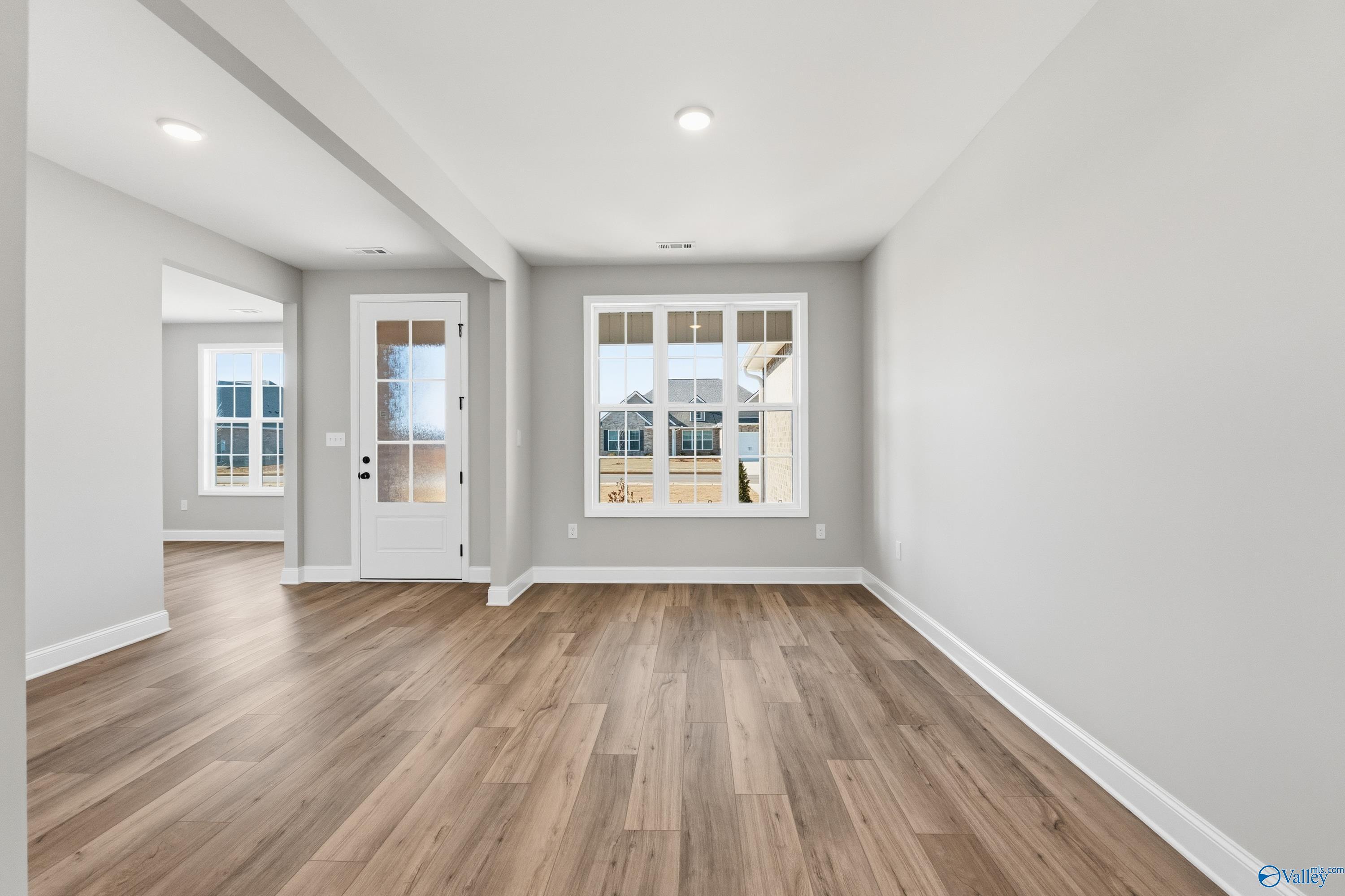 Bright living room with hardwood floors, large windows and French doors in The Finleigh home, Meridianville, Alabama