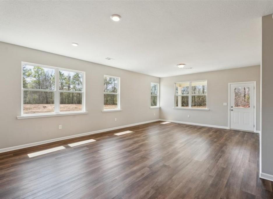 Bright living room with large windows, hardwood floors, and recessed lighting in Evermore Homes The Aurora A, Cusseta, Alabama